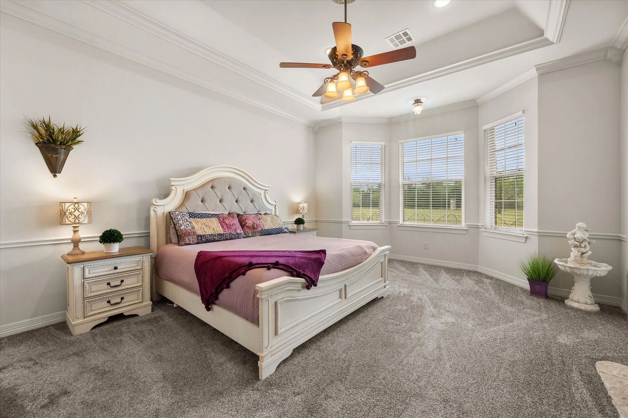 Spacious bedroom featuring a tray ceiling with crown molding, a ceiling fan, and recessed lighting