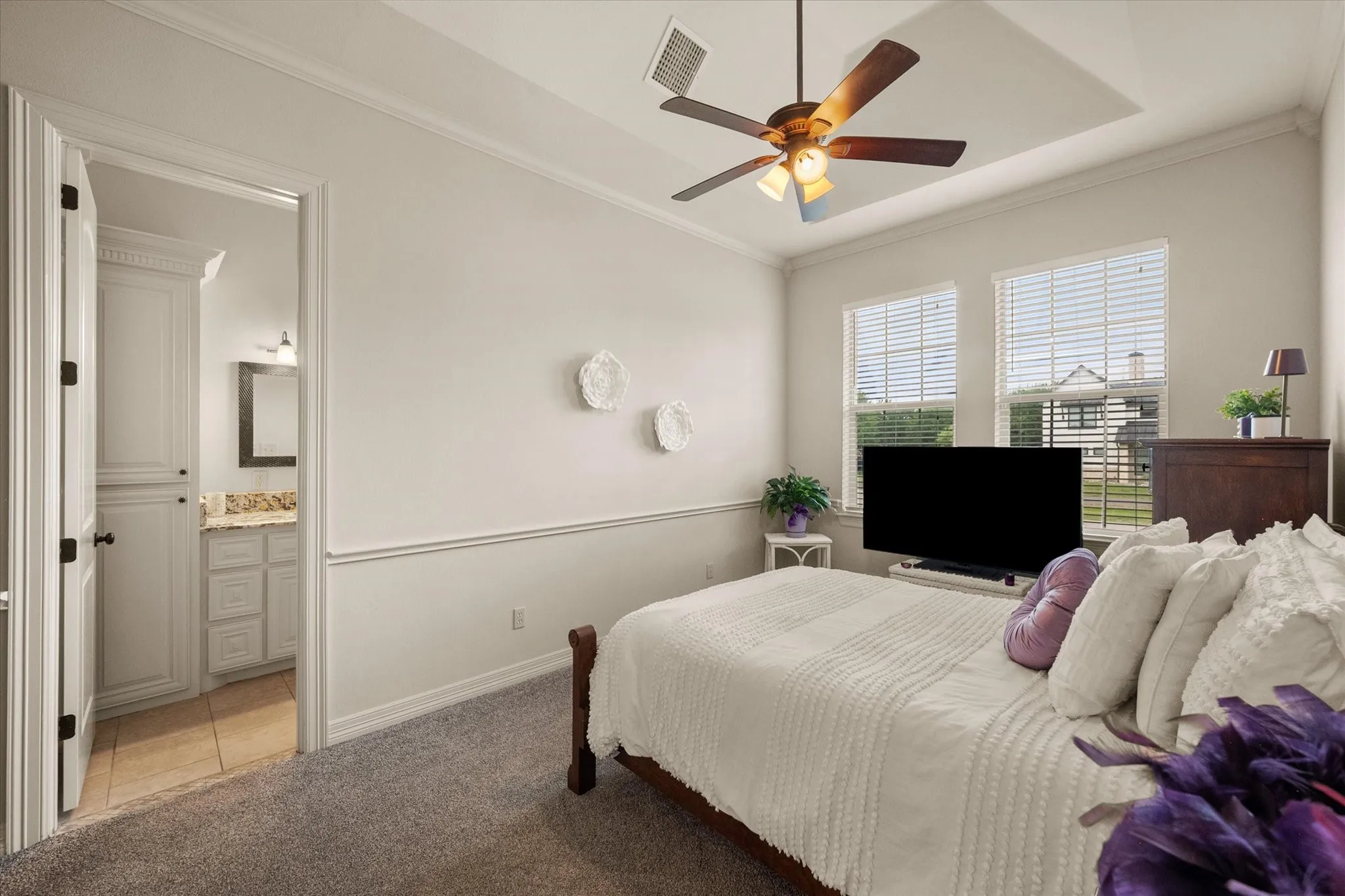 Guest bedroom with tray ceiling and ceiling fan and ensuite bathroom