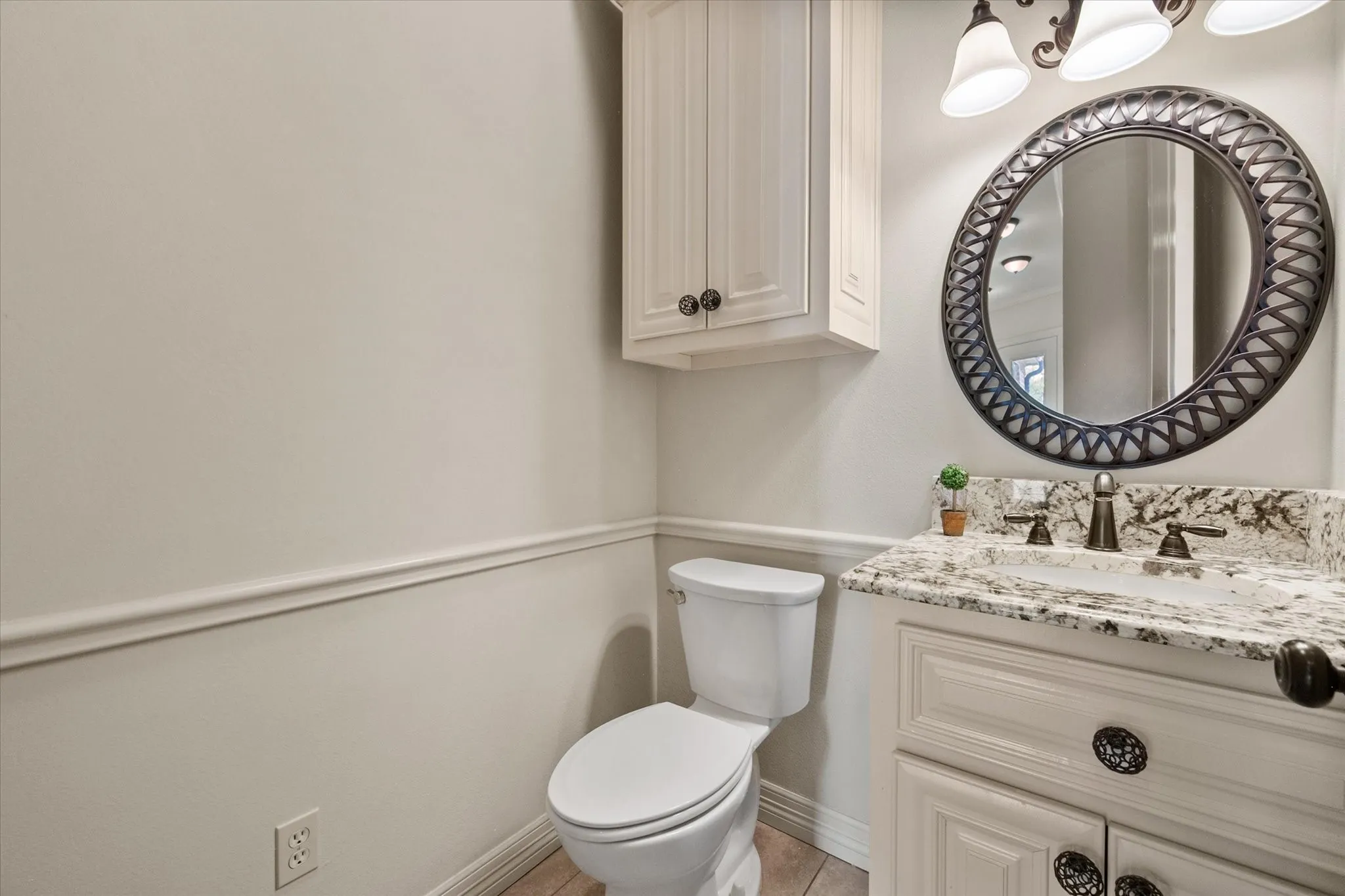 Half bath featuring vanity with granite-style countertop, undermount sink, and oil-rubbed bronze faucet