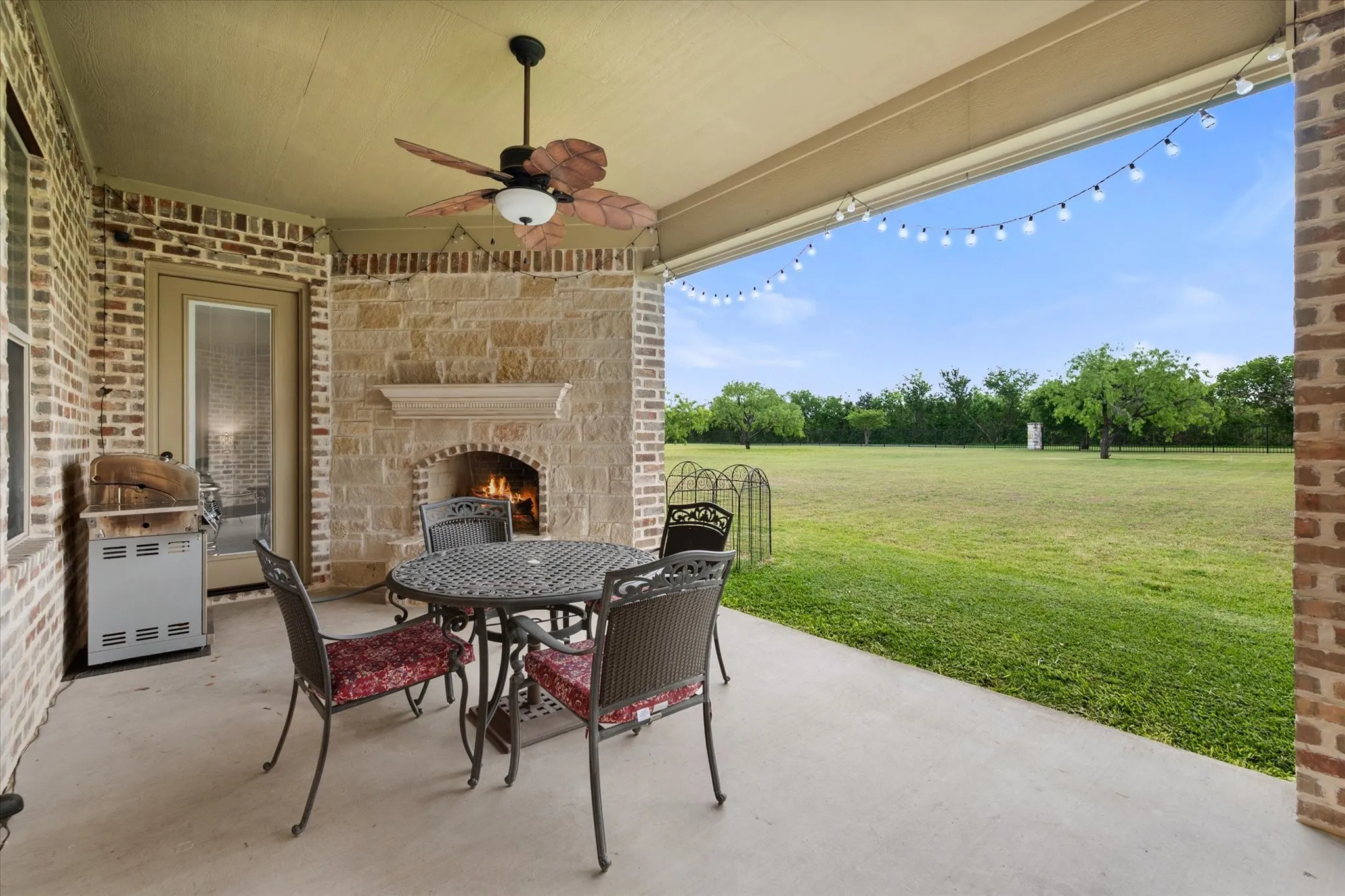 Covered patio with a stone fireplace and ceiling fan