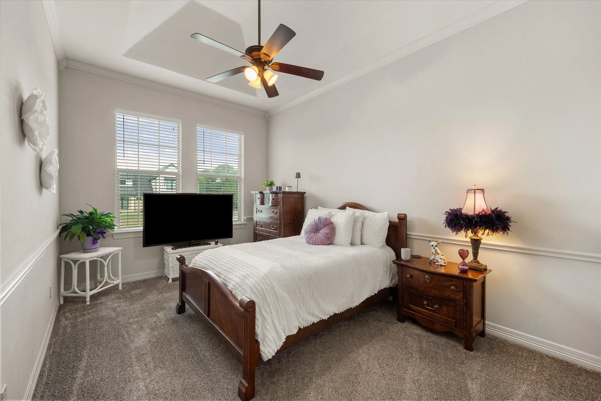 Guest bedroom featuring a tray ceiling with a ceiling fan