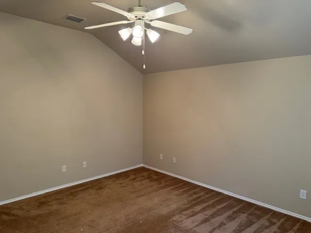Vaulted ceiling room with textured walls, brown carpet, and white baseboards