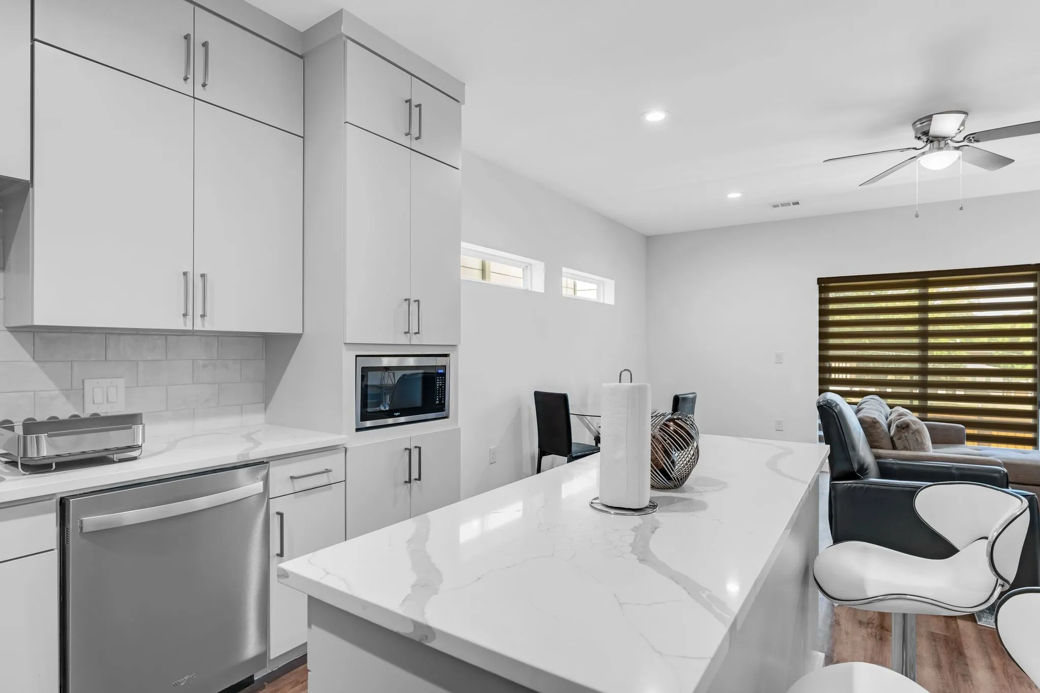 The kitchen features white cabinetry, white countertops, a built-in microwave, and a stainless steel dishwasher