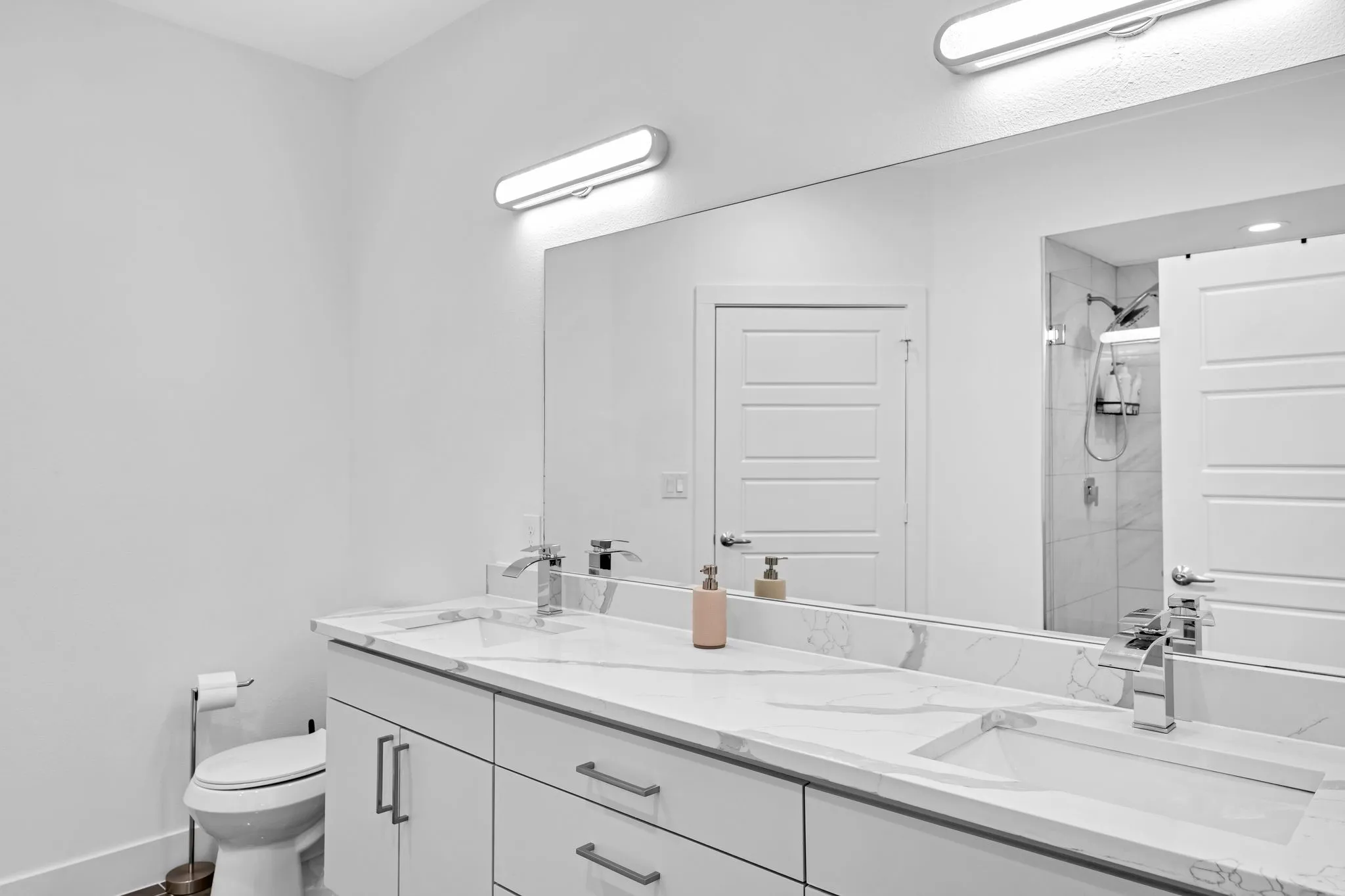 Bathroom featuring a dual vanity with undermount sinks, chrome fixtures, and a spacious mirror