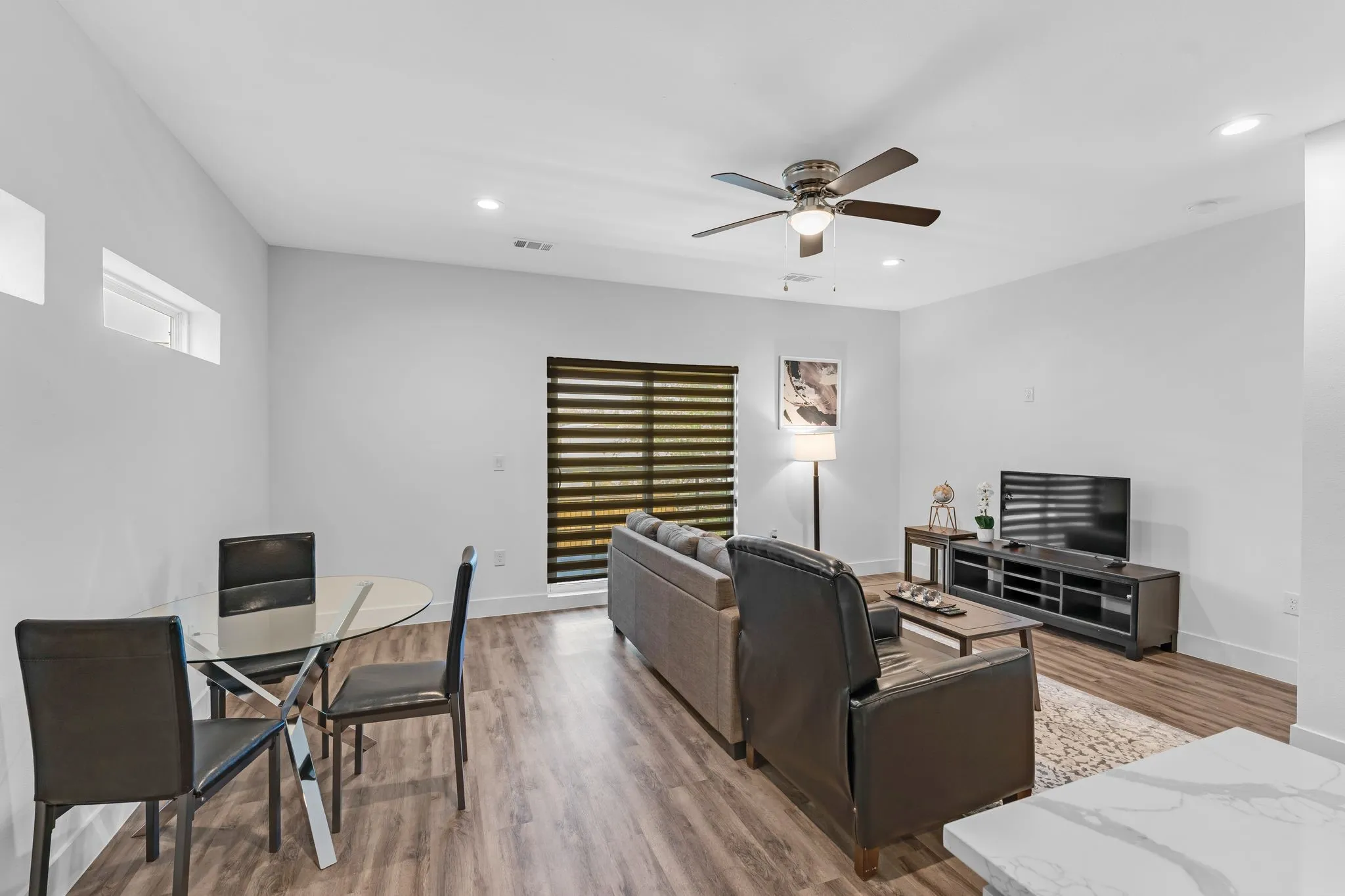 This living space features wood-style flooring, a ceiling fan, and recessed lighting
