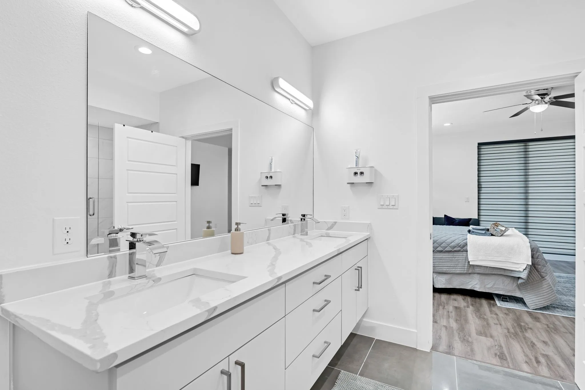 Bathroom featuring a double vanity with a marble-patterned countertop, dual sinks, and modern light fixtures