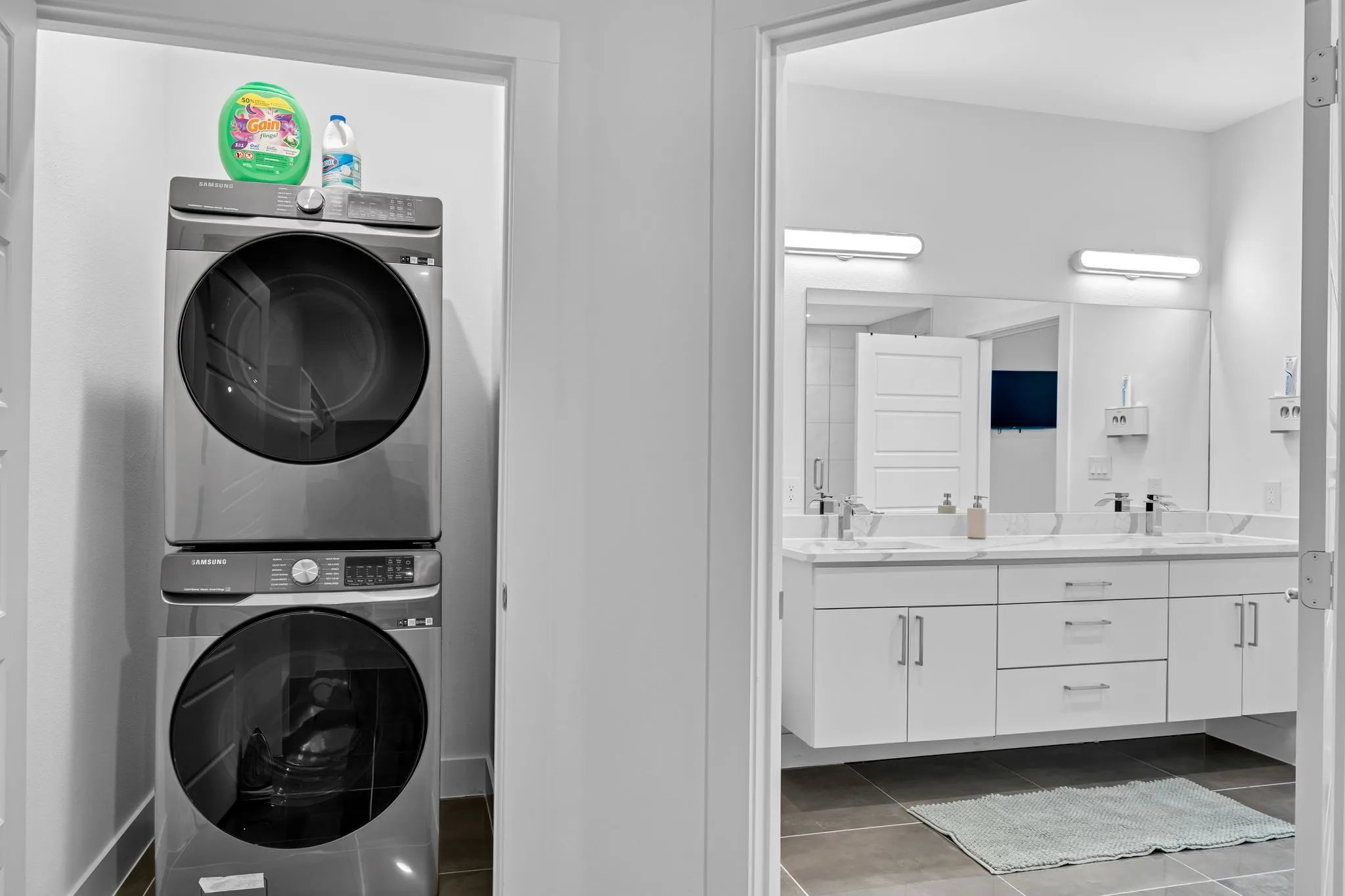 The property features a dedicated laundry area with a stacked washer and dryer, conveniently located near a bathroom with a floating vanity, dual sinks, and a large mirror