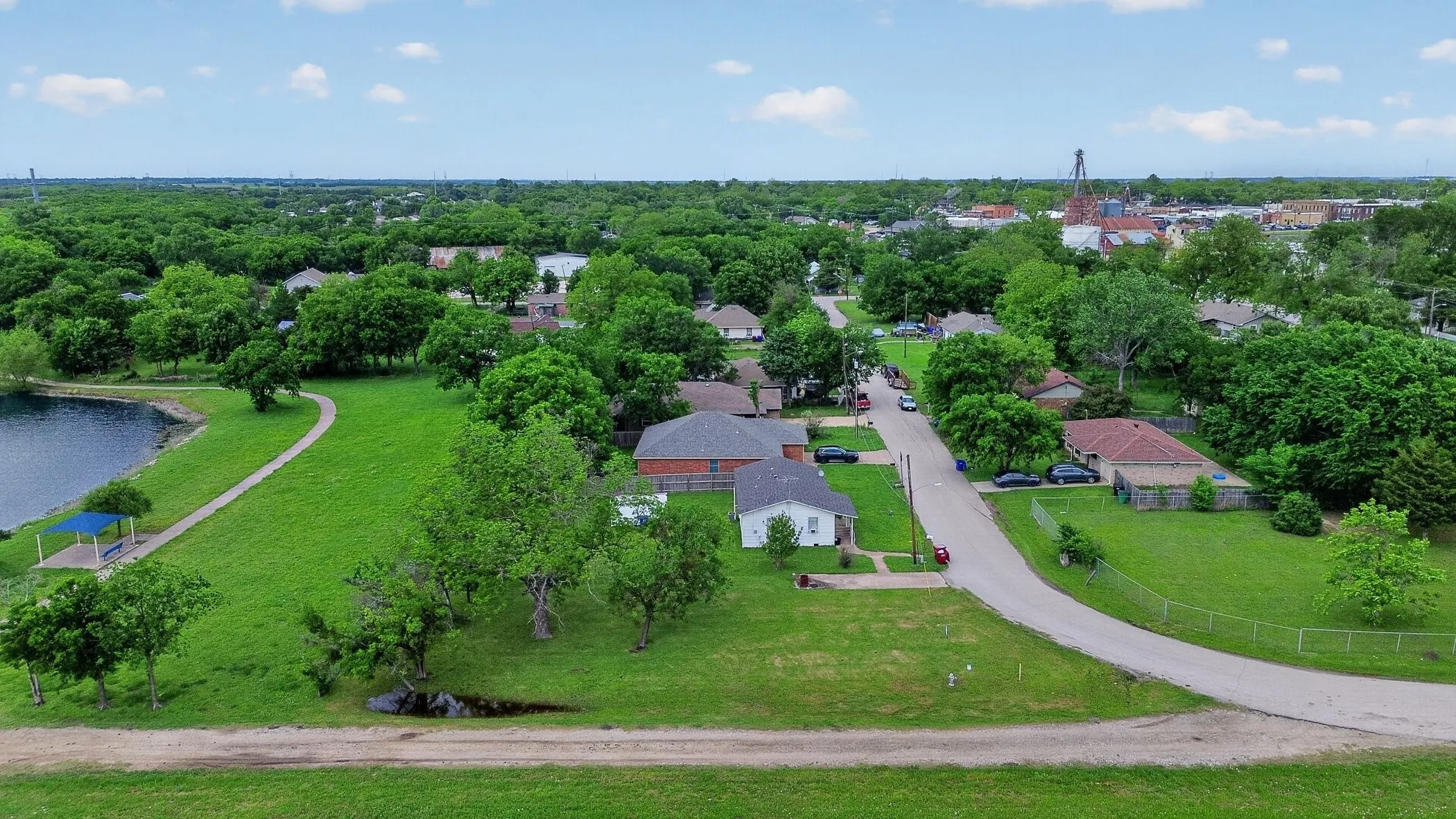 Expansive green space and a serene body of water with a paved path