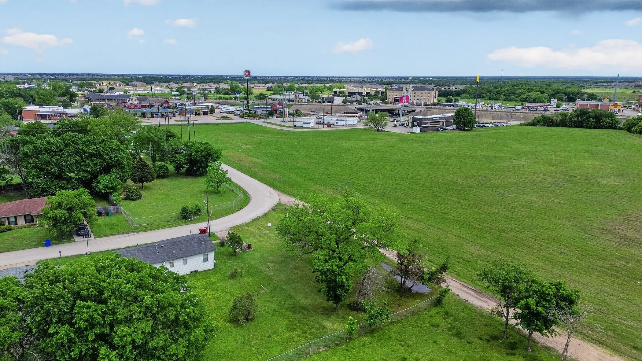 Expansive green acreage with a curved paved road