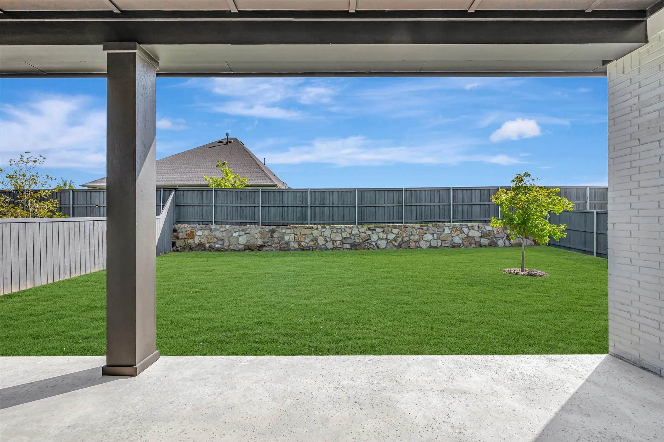 Covered patio with a concrete surface, overlooking a spacious lawn
