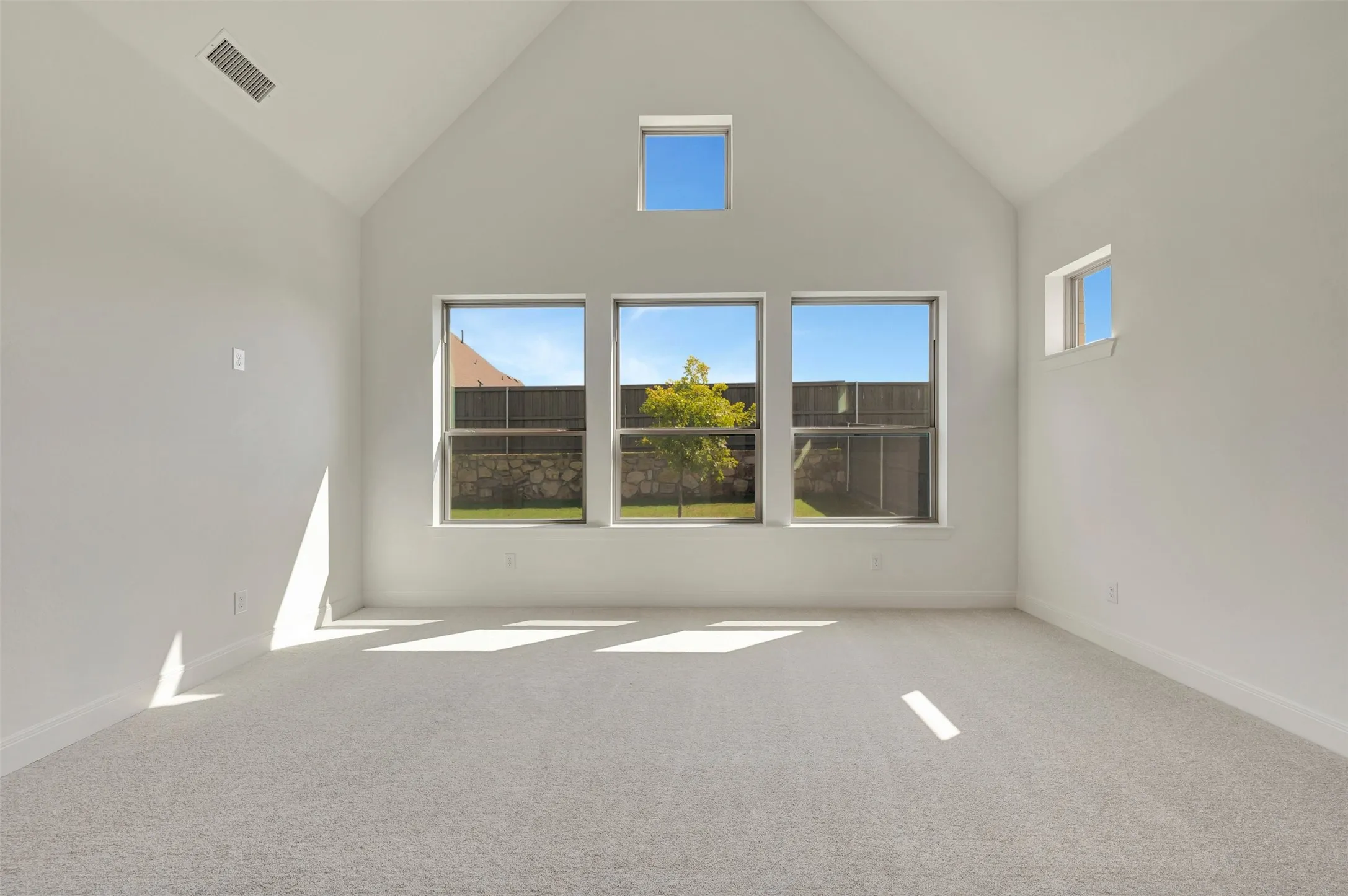 Room featuring a high vaulted ceiling, neutral wall paint, and light-colored carpet flooring