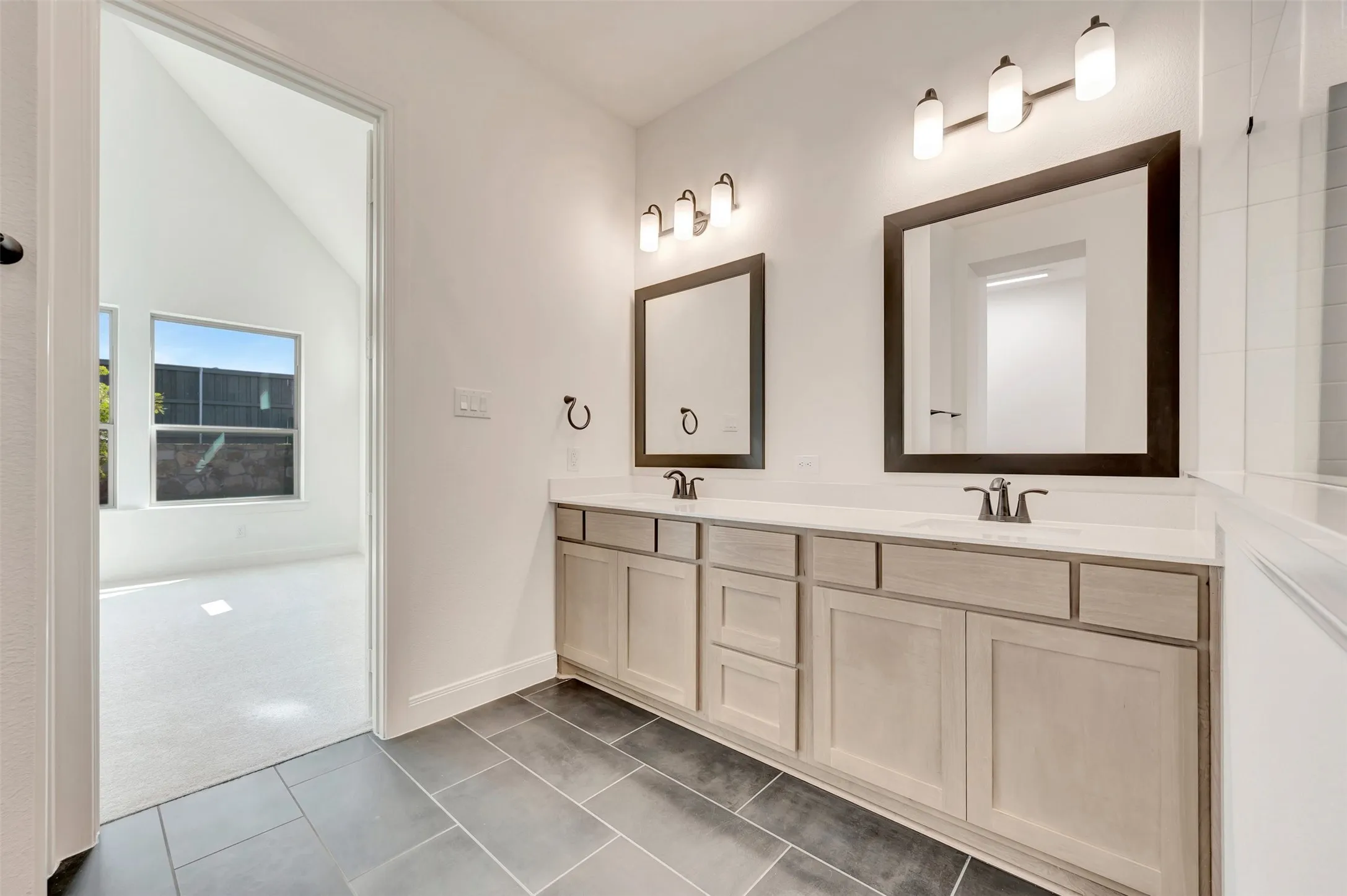 Bathroom featuring a dual vanity with light-toned cabinetry, solid surface countertops, and rectangular undermount sinks