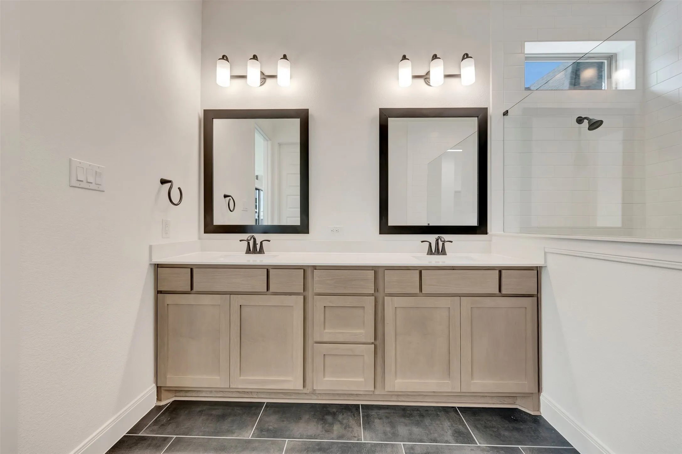 Dual vanity with light wood-finish cabinetry and white countertops