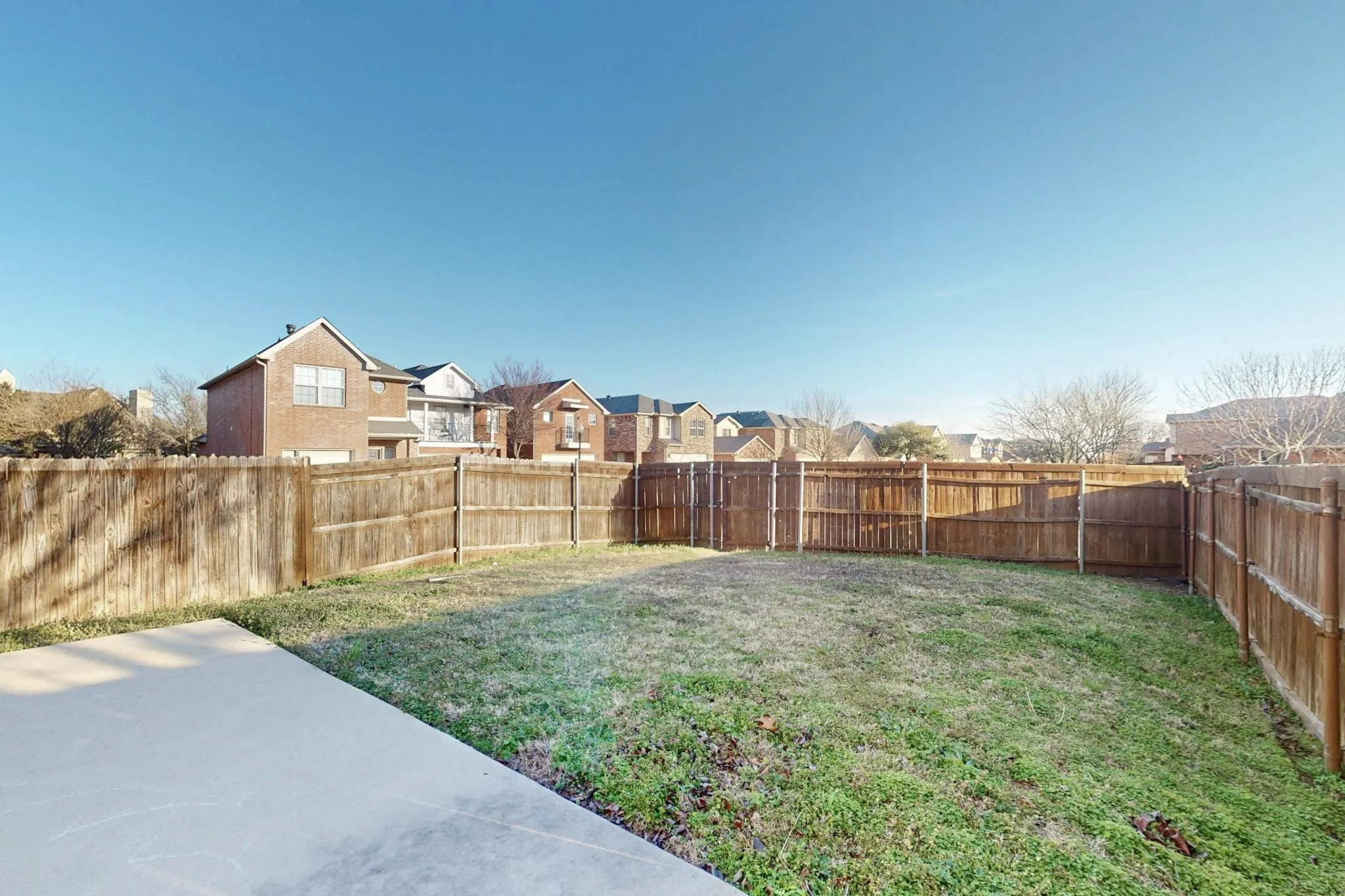 Expansive backyard featuring a wood privacy fence, a concrete patio, and a grassy lawn