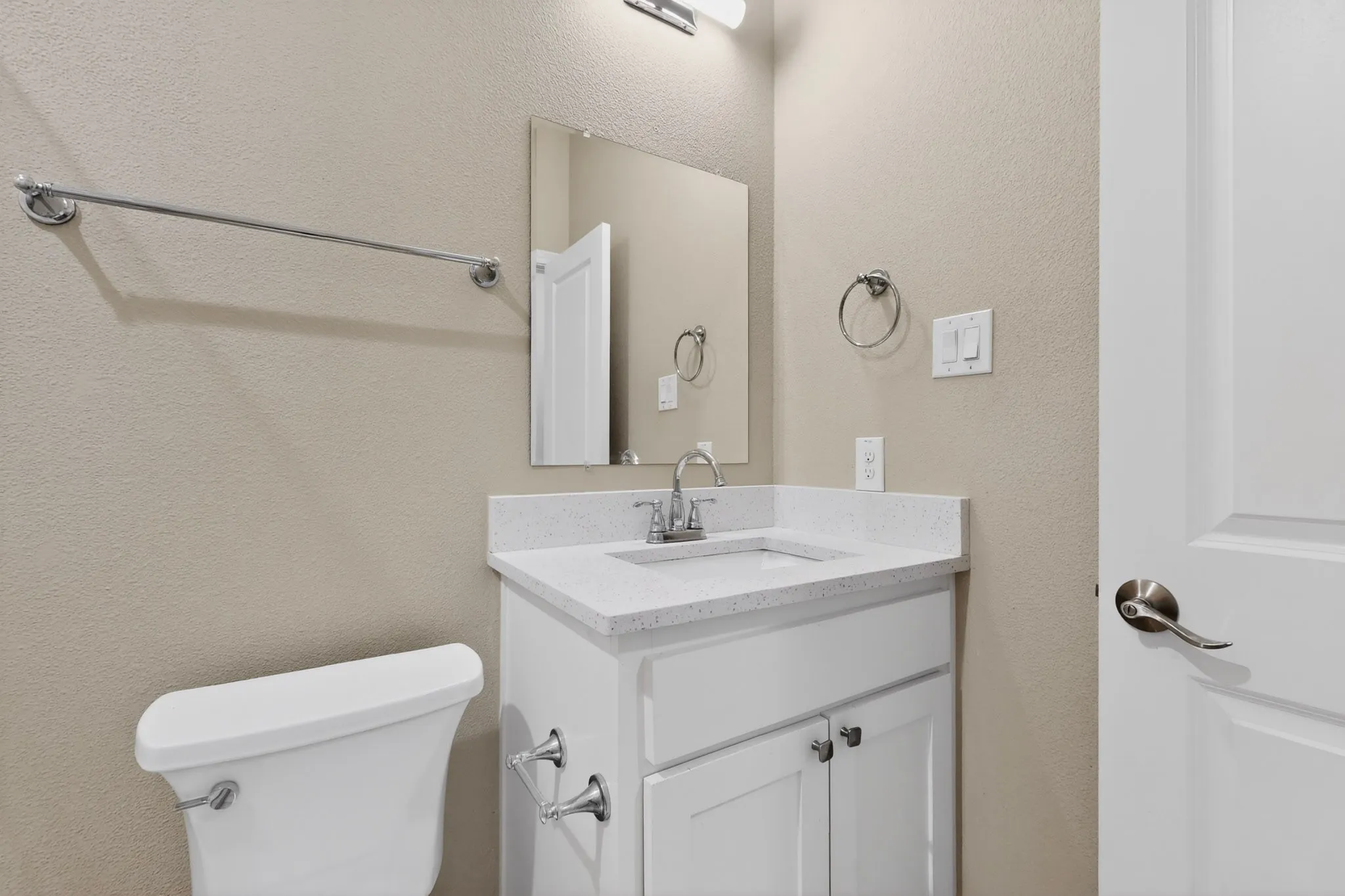Bathroom featuring a white vanity with a light-toned countertop, a rectangular mirror, and chrome fixtures