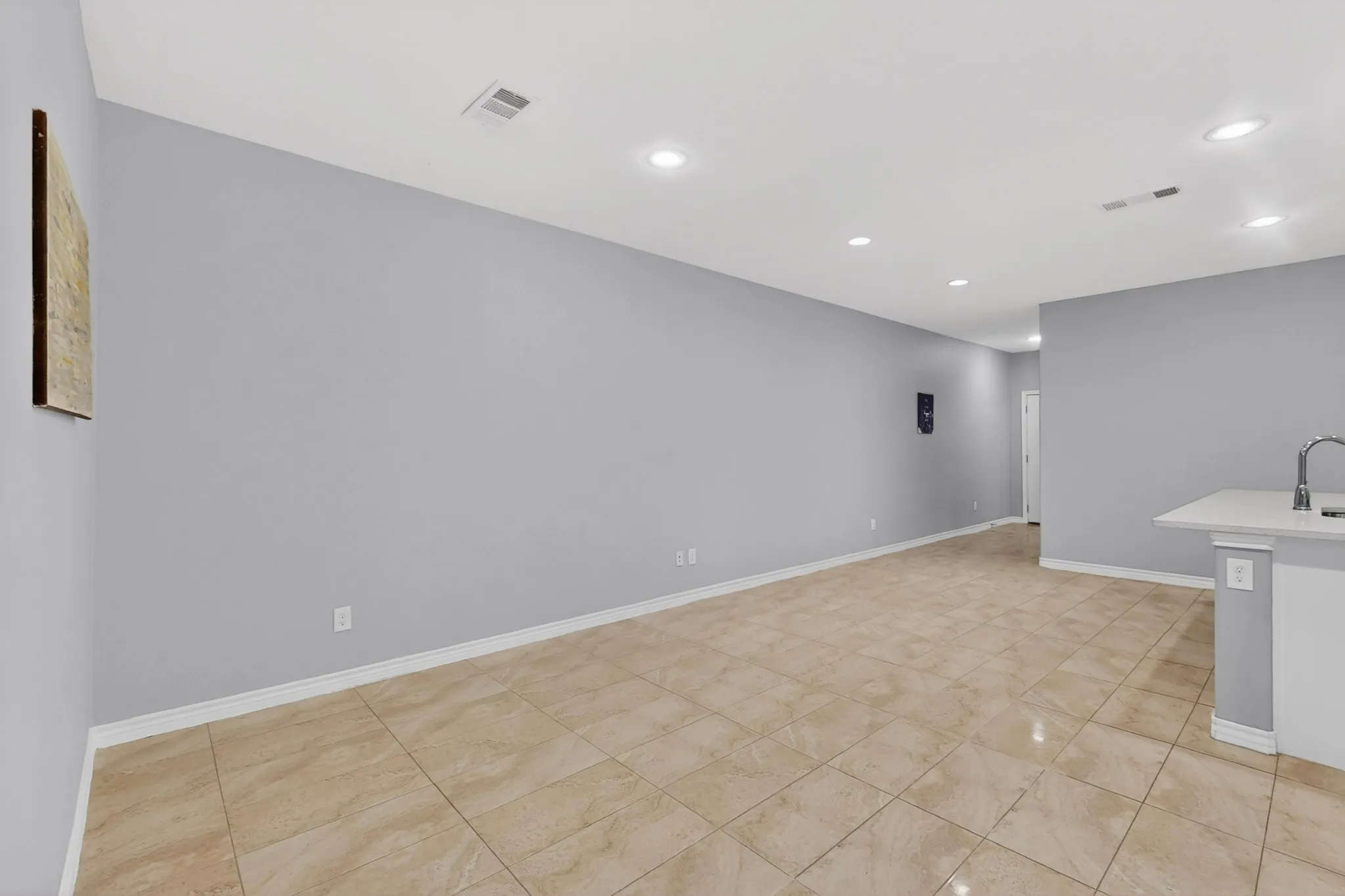 Spacious interior featuring large format tile flooring, light gray walls, recessed lighting, and white baseboards