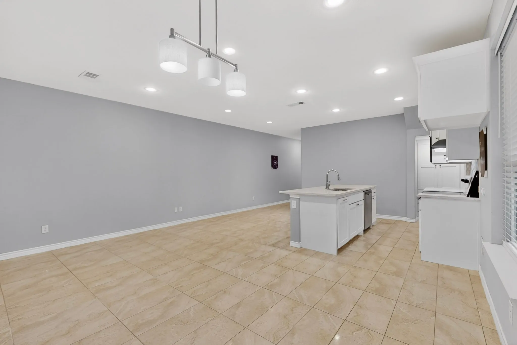 Open-concept living space featuring neutral tile flooring, recessed lighting, and a contemporary linear chandelier