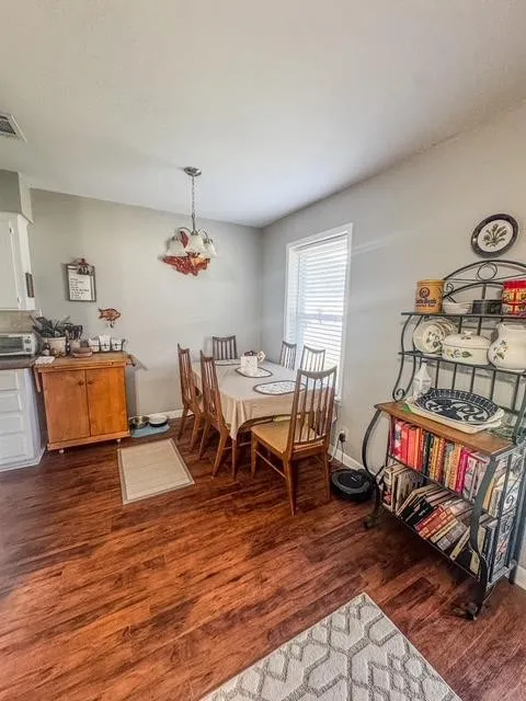 Dining area featuring wood-finish flooring, a window with blinds, and an overhead light fixture