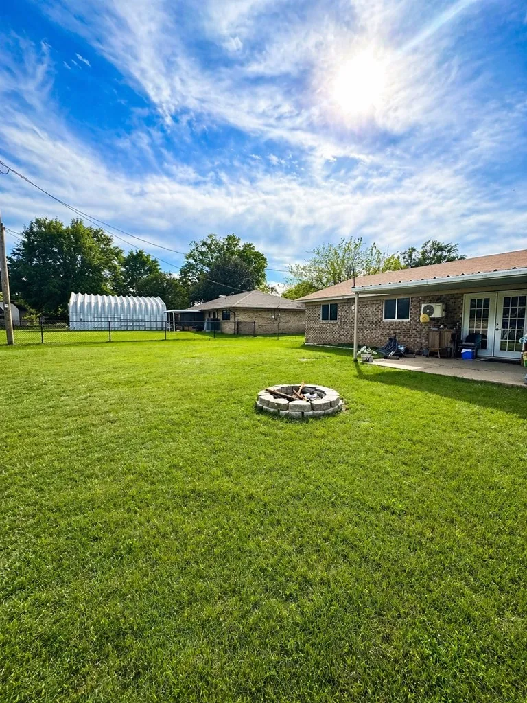 Spacious backyard featuring a stone-ringed fire pit and extensive lawn