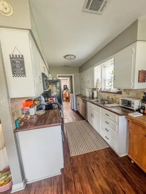 Galley kitchen featuring wood-finish flooring, white cabinetry, and wood-finish countertops