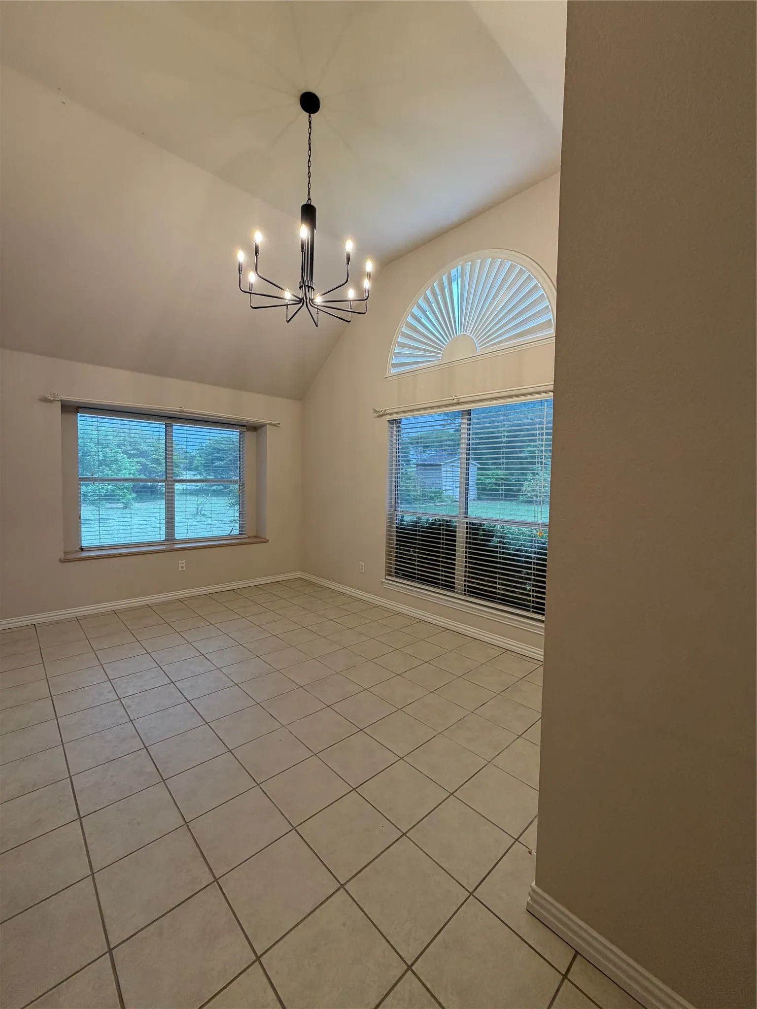 3RD Spacious room featuring vaulted ceilings, a contemporary multi-arm chandelier, built in desk and large windows