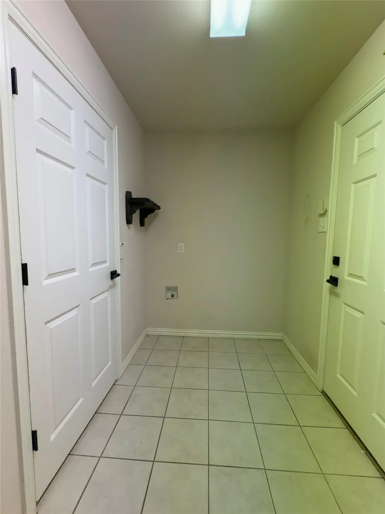 Utility area featuring plenty of room for additional refrigerators or deep freezer. light tile flooring, white baseboards, and neutral wall paint