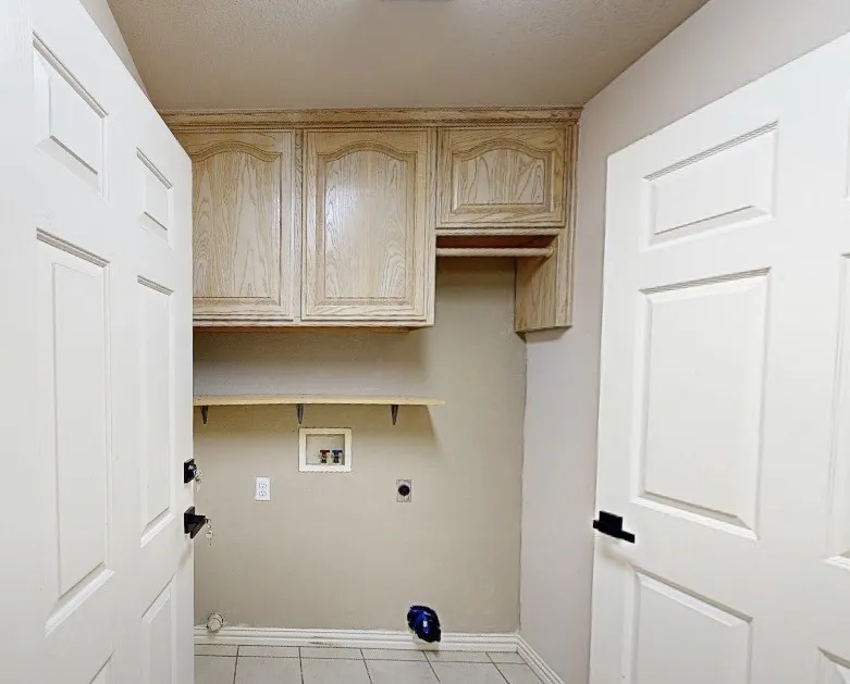 Utility space featuring light wood-finish cabinetry, a floating shelf, and neutral wall tones