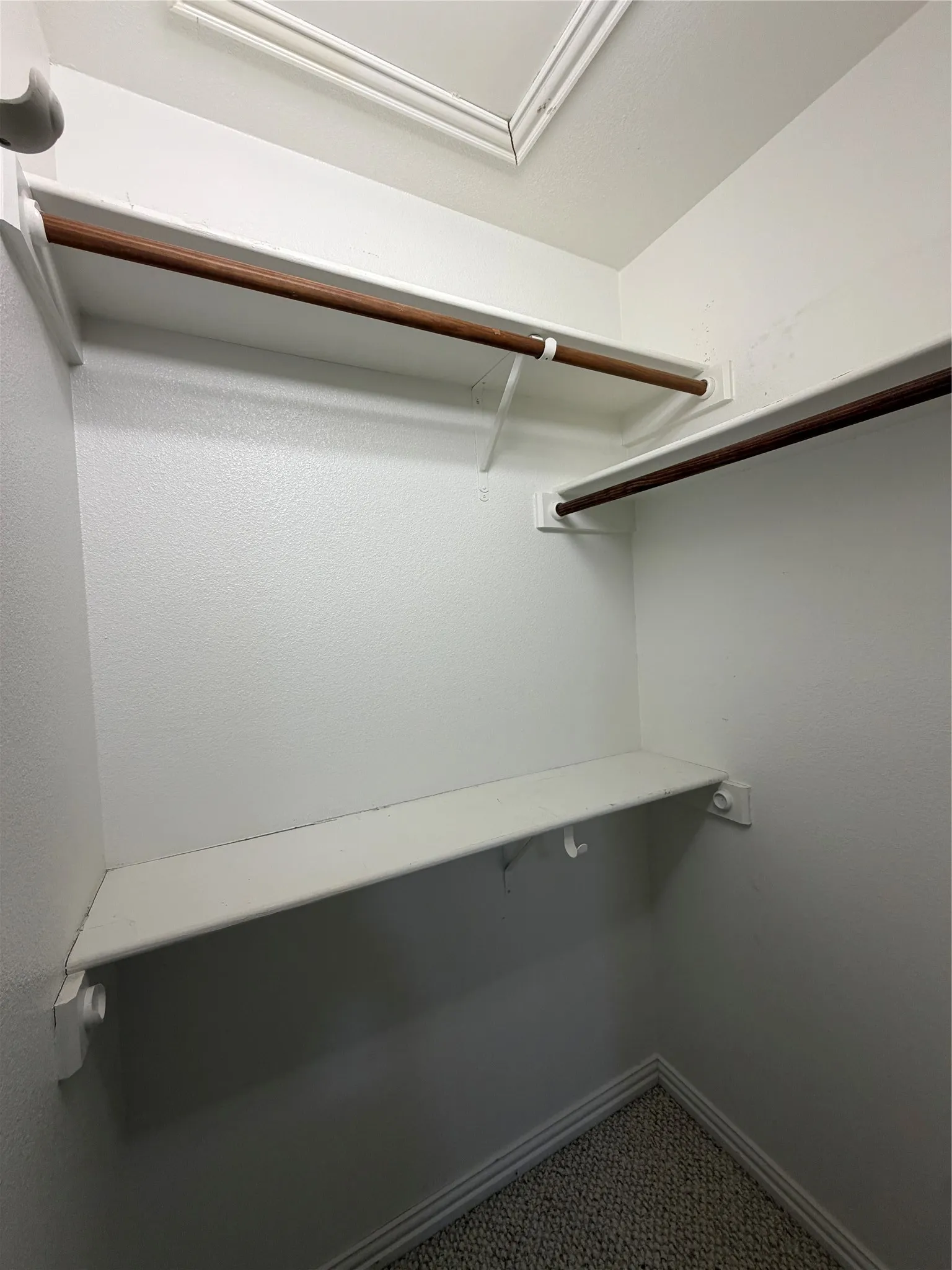 2nd bedrooms Interior closet with white walls, two clothing rods, and a lower storage shelf