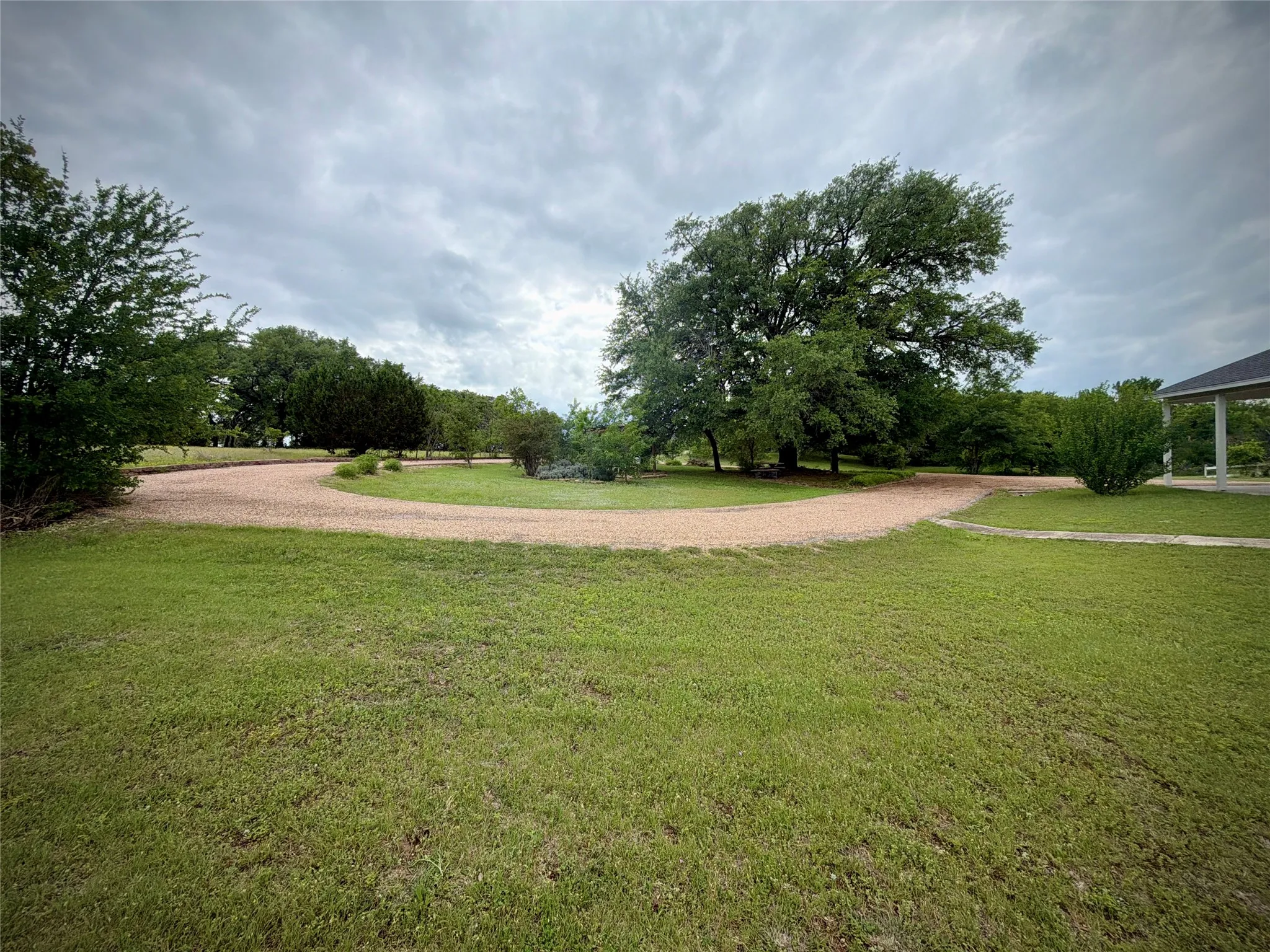 Expansive full circle gravel driveway winding through mature trees and lush green lawn