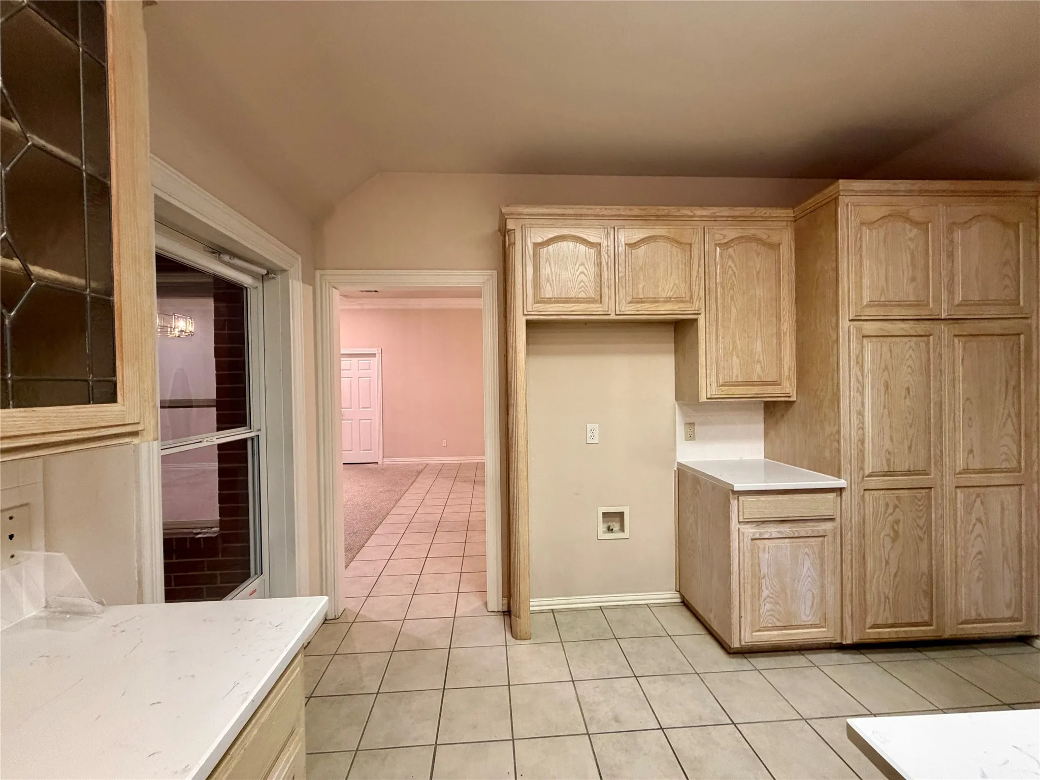 Kitchen featuring light wood-finish cabinetry, white solid surface countertops, and square tile flooring
