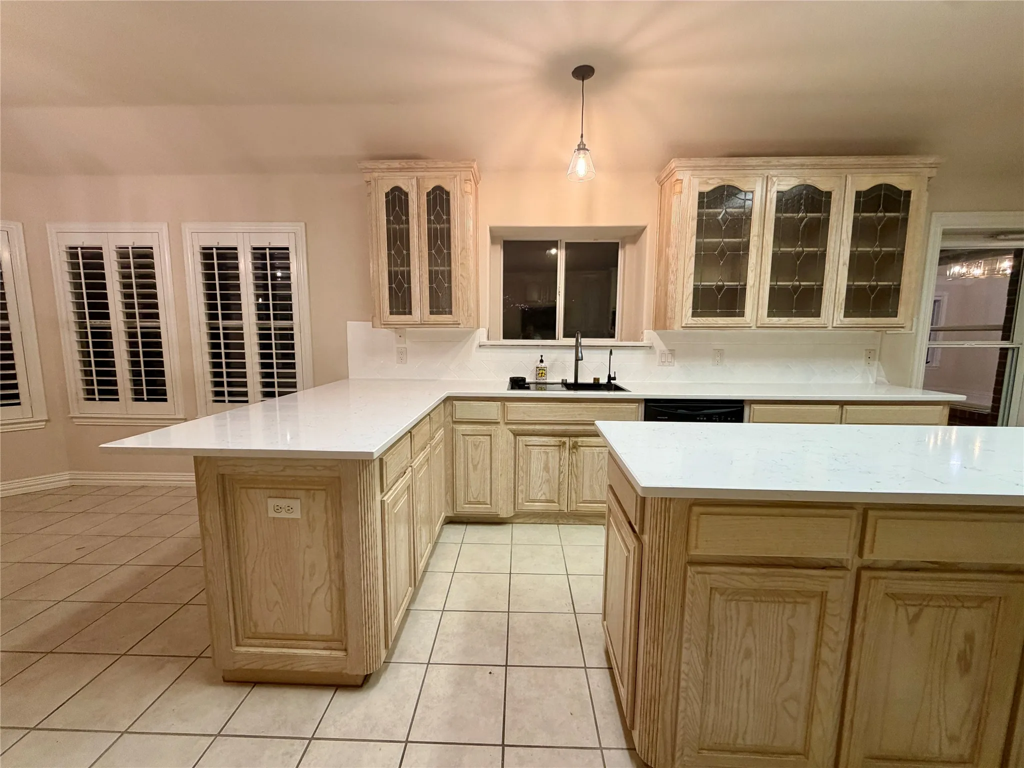 Kitchen featuring light wood cabinetry, white countertops, tile flooring, and a central island