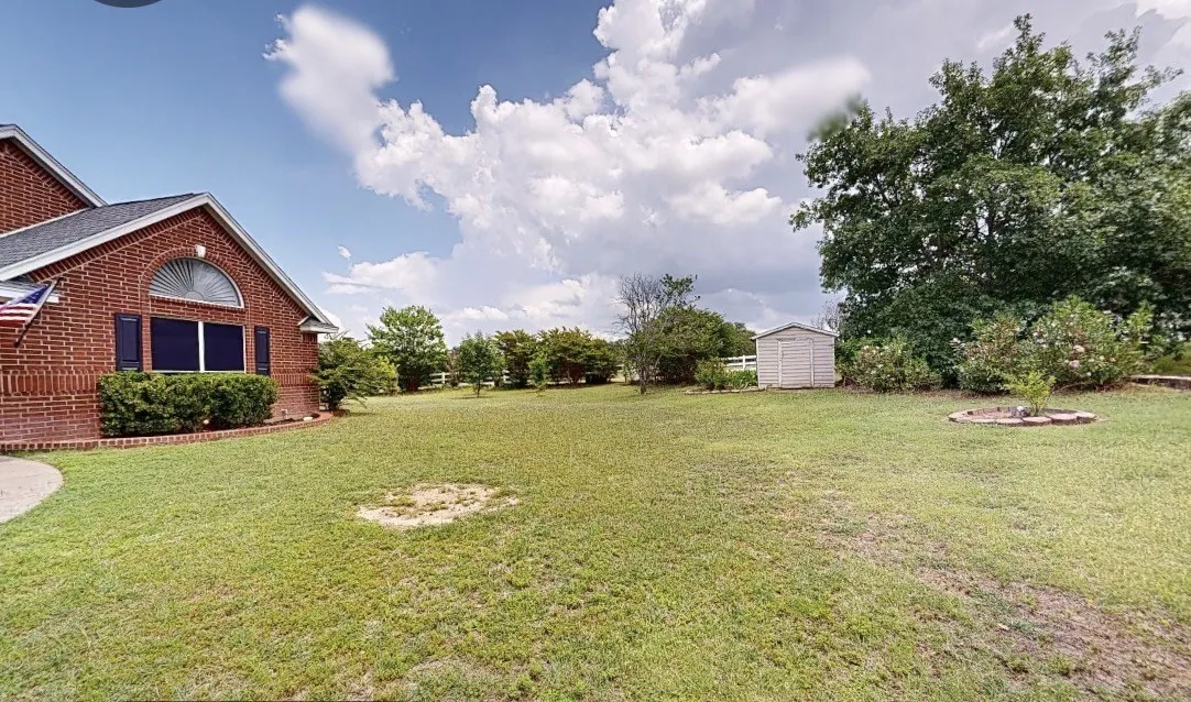 Expansive green lawn with mature trees and a dedicated storage shed