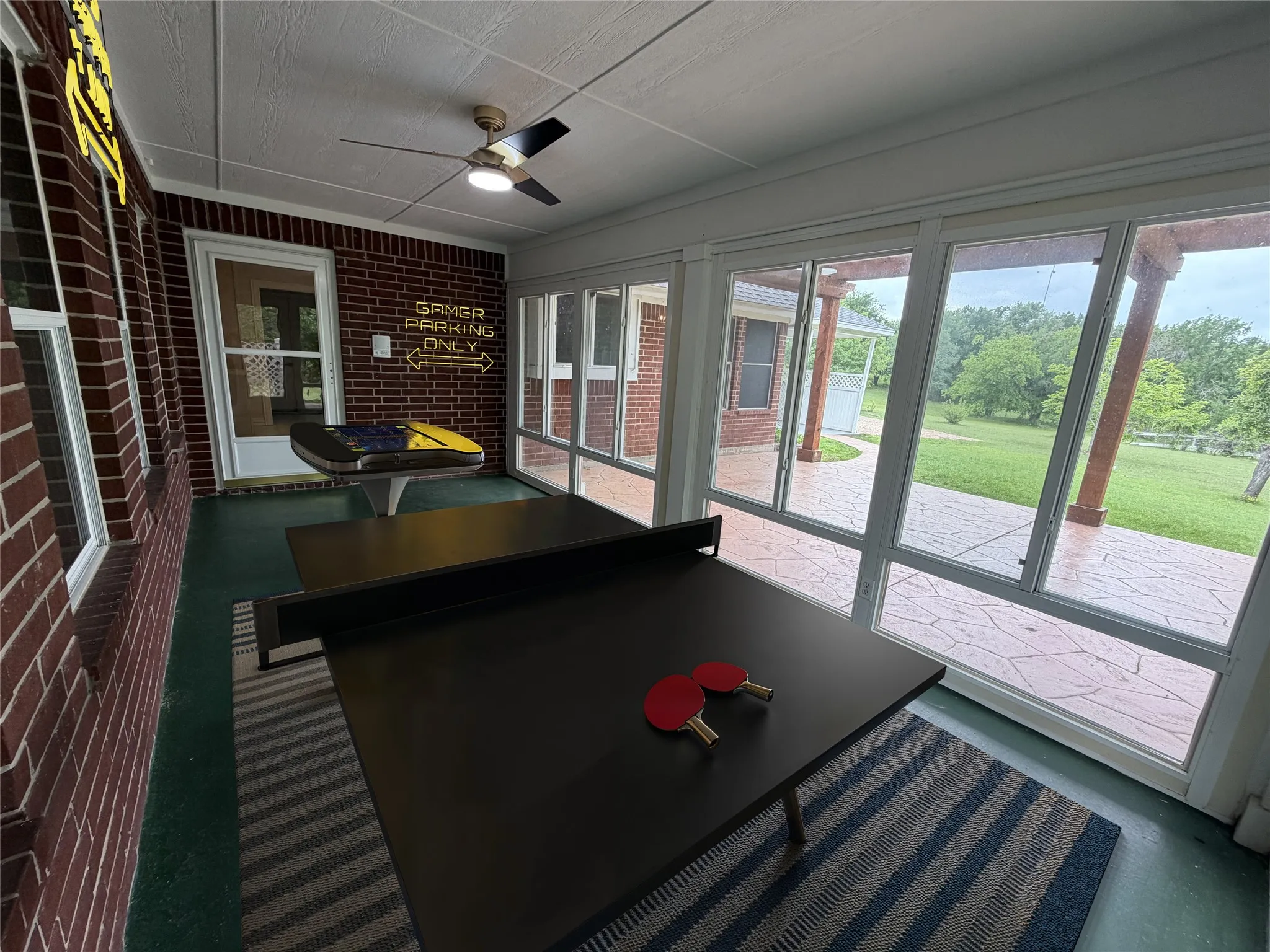 Sunroom featuring extensive window panels, a brick accent wall, and a ceiling fan