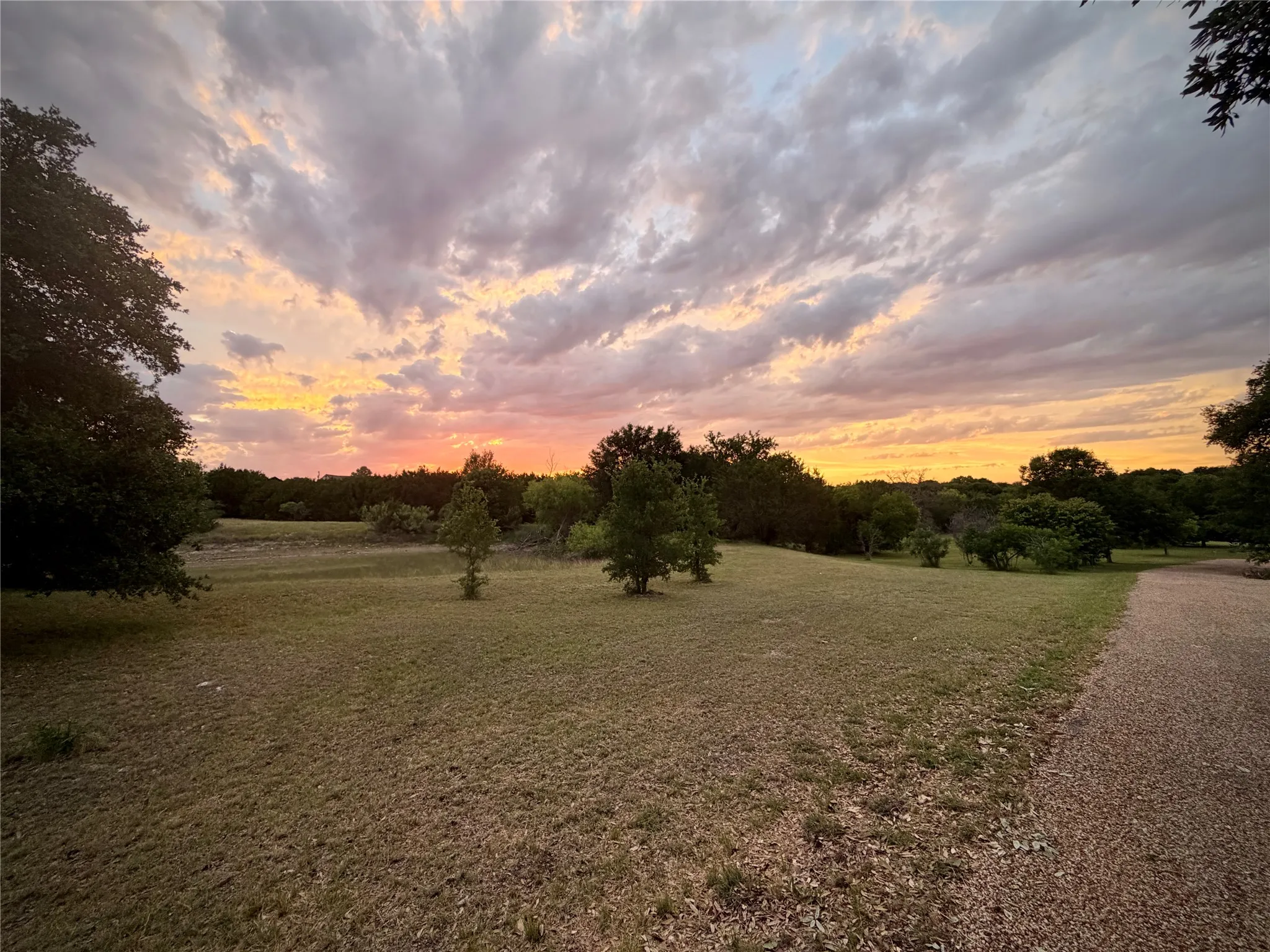 THESE ARE REAL SUNSETS!! Expansive grassy area with scattered mature trees and a gravel pathway