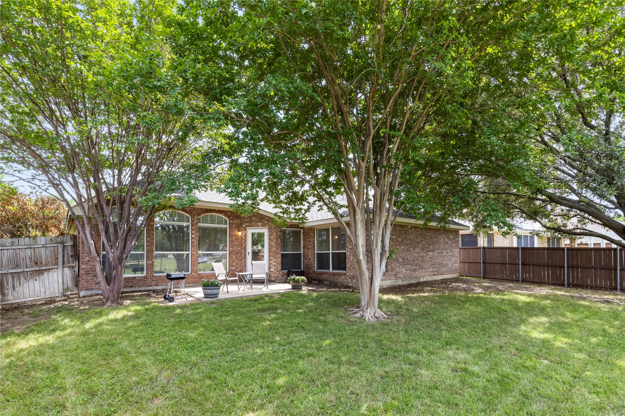 Shaded back yard overlooking green space.