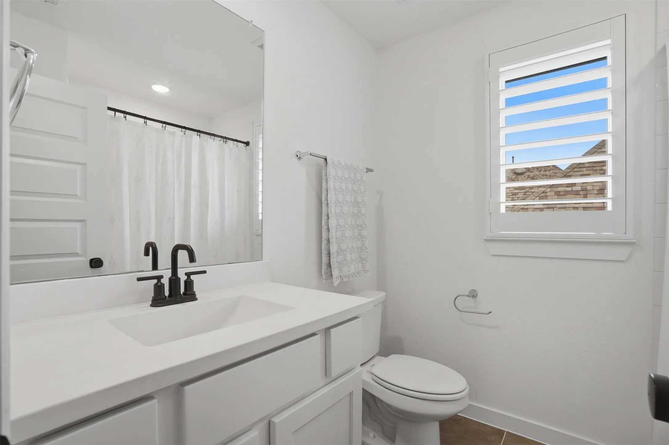 Bathroom vanity with an integrated sink, matte black faucet, and frameless mirror