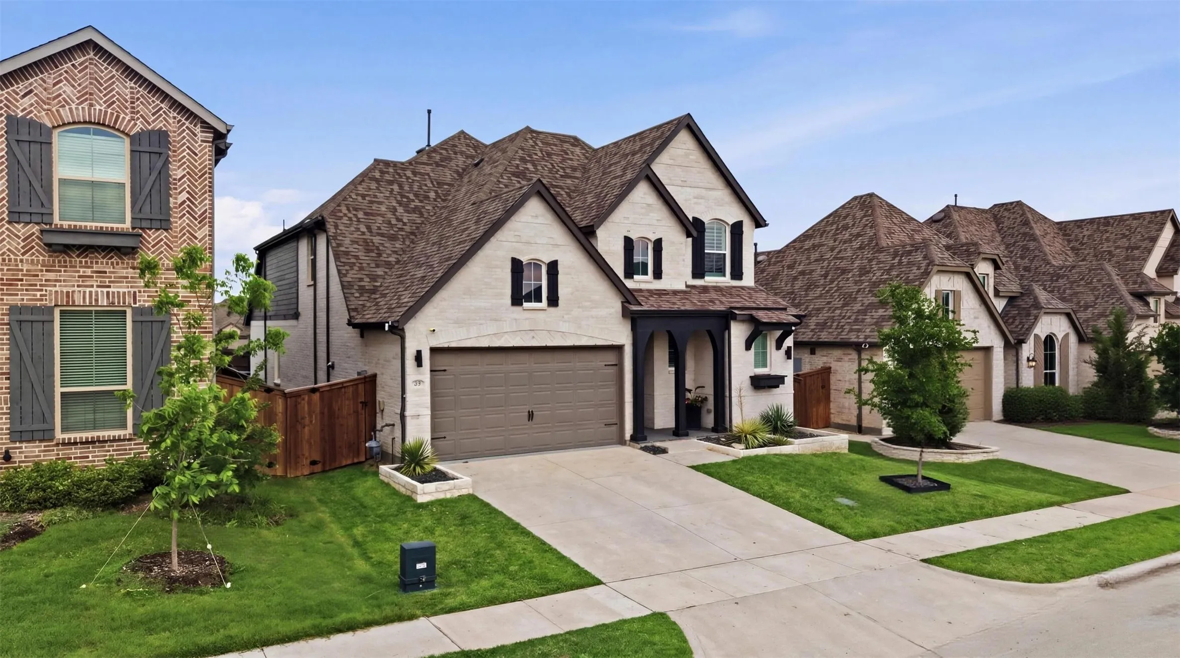 Two-story residence featuring light-colored brick and dark trim accents