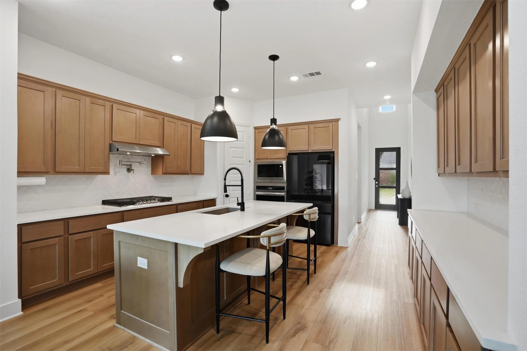 Kitchen featuring a central island with countertop seating, wood-finish flooring, recessed lighting, and pendant fixtures