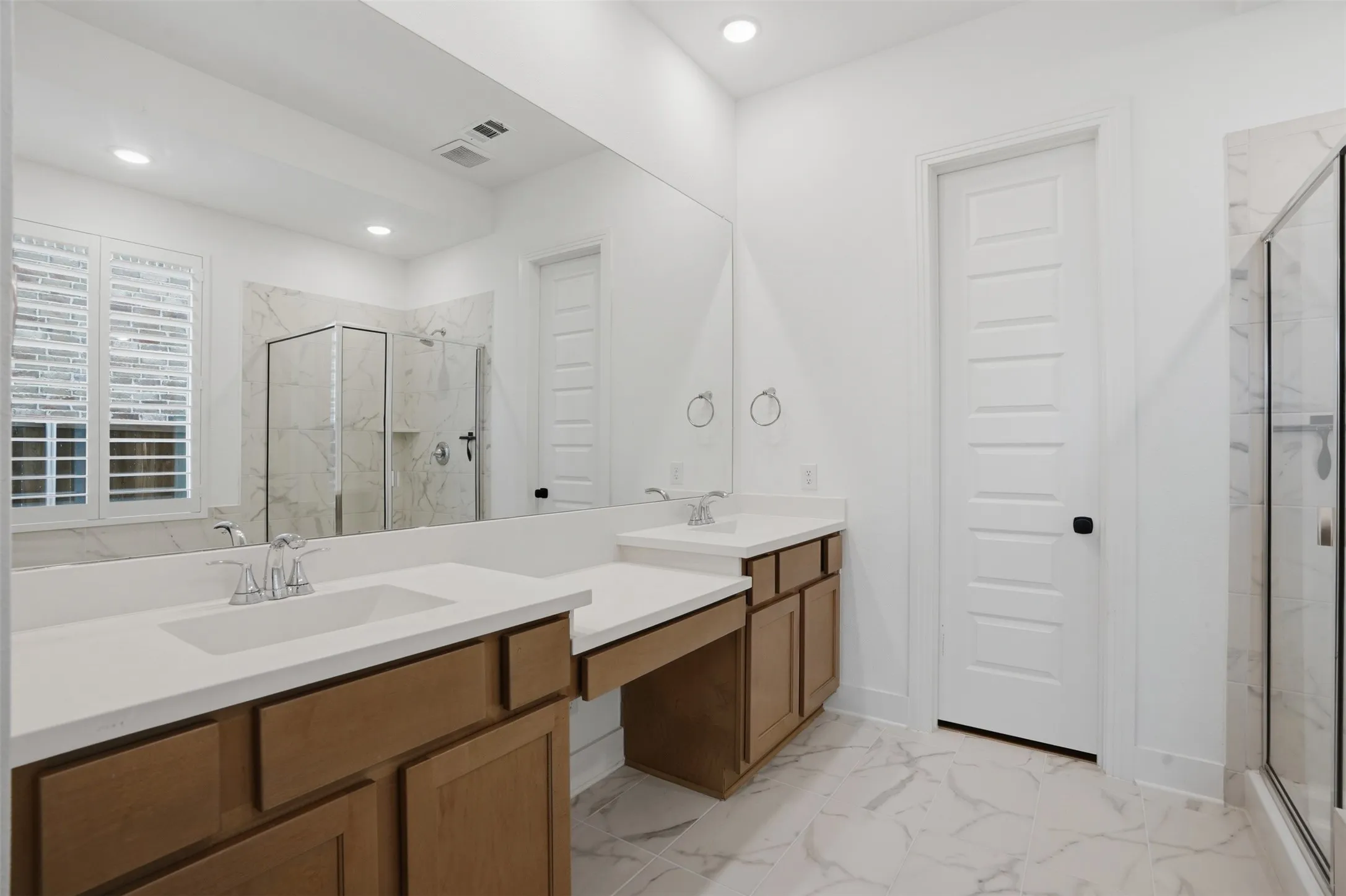 Bathroom featuring a dual vanity with light wood cabinetry and solid surface countertops