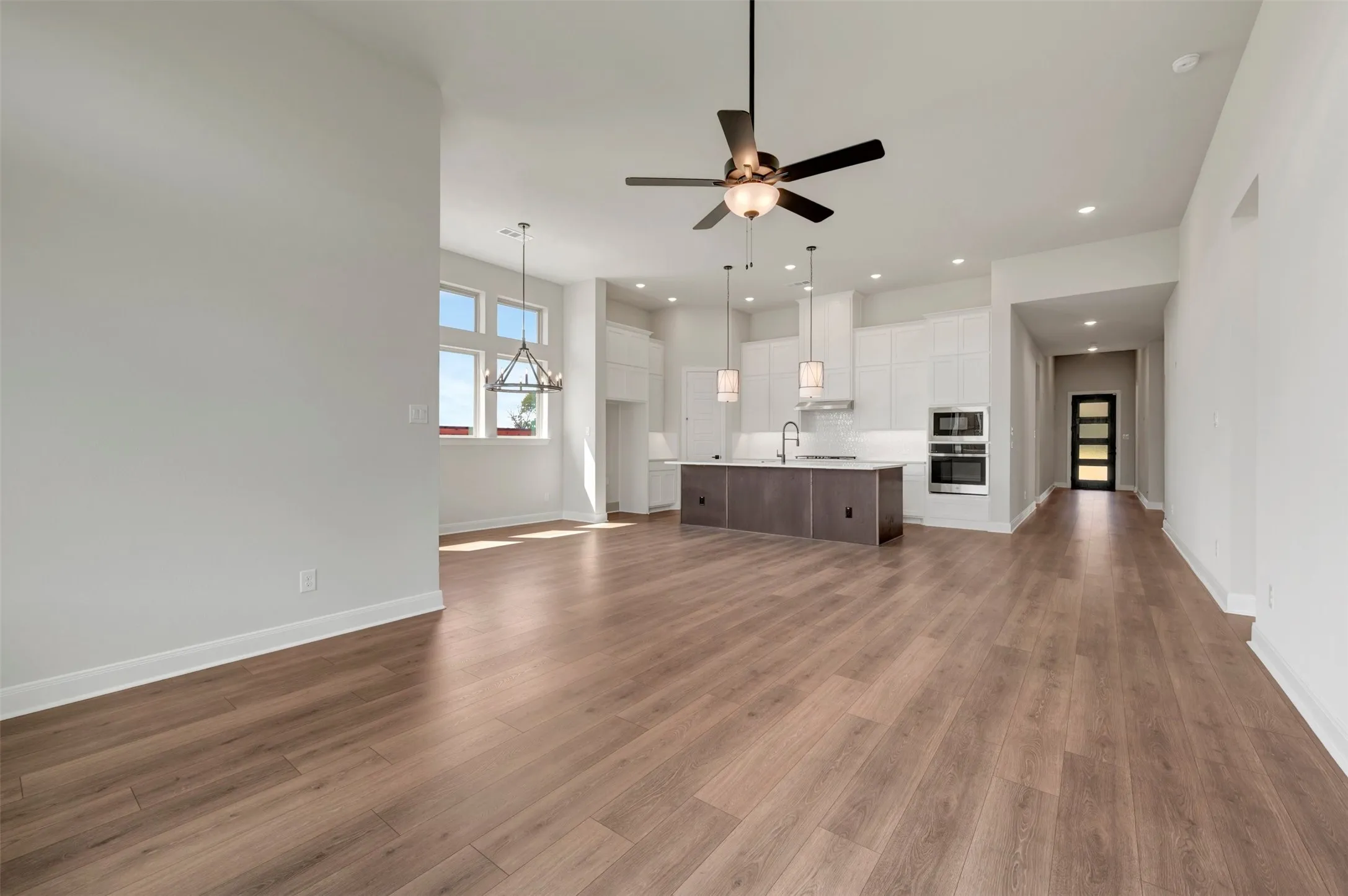 Open-concept living space featuring wood-finish flooring, recessed lighting, and a modern kitchen with a large island