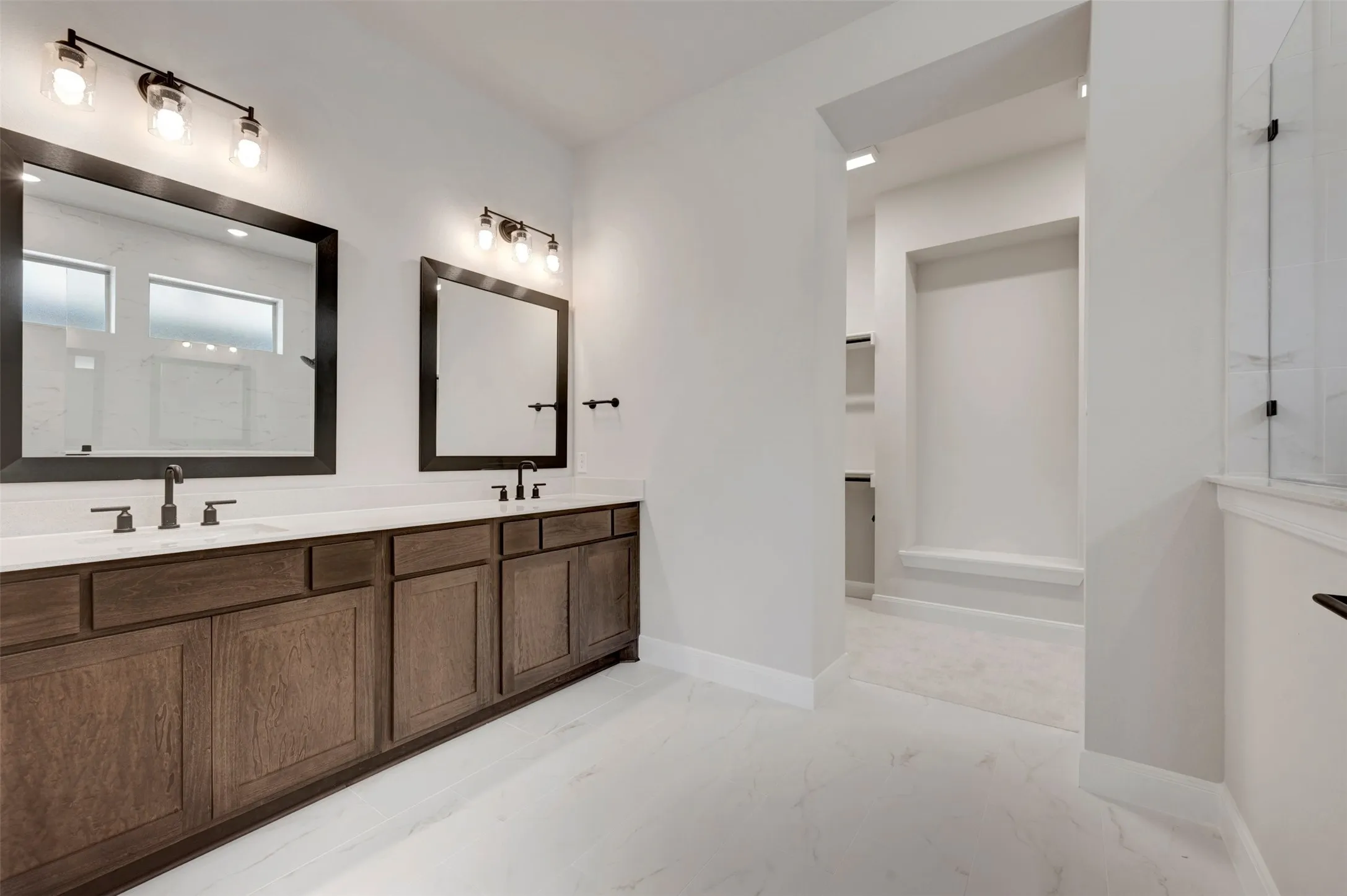 Dual vanity with dark wood-finish cabinetry, countertop, and individual framed mirrors