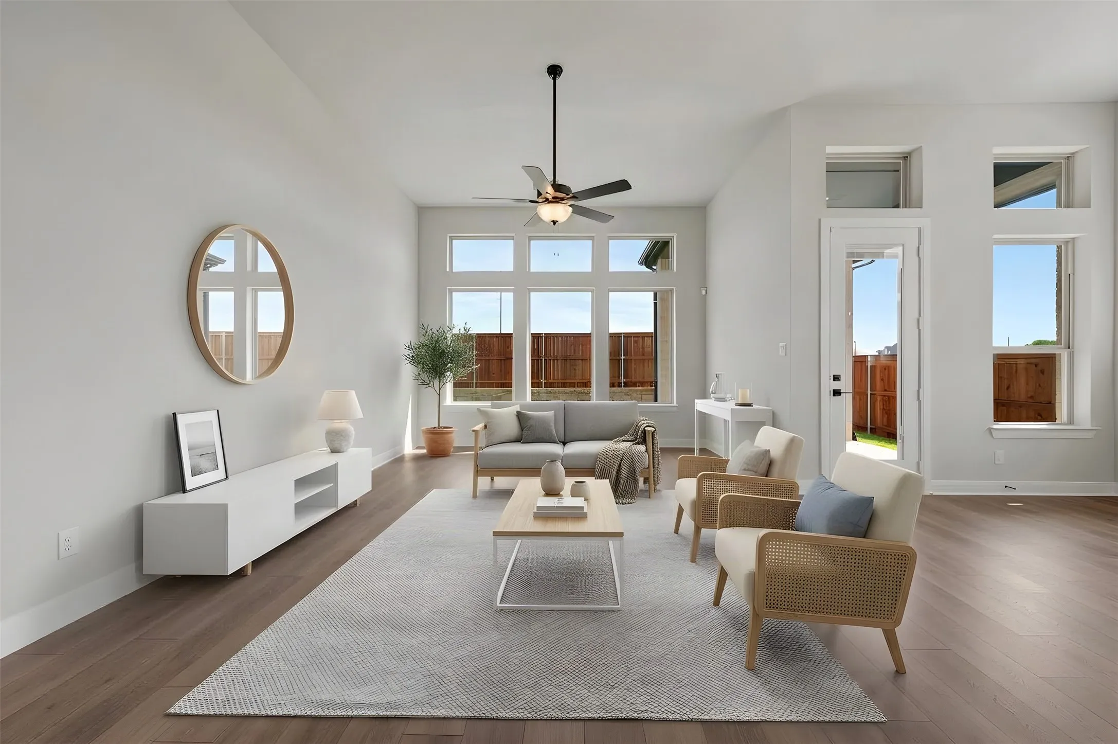 Vaulted ceiling with a ceiling fan, wood-finish flooring, multiple windows, and a glass-paneled exterior door