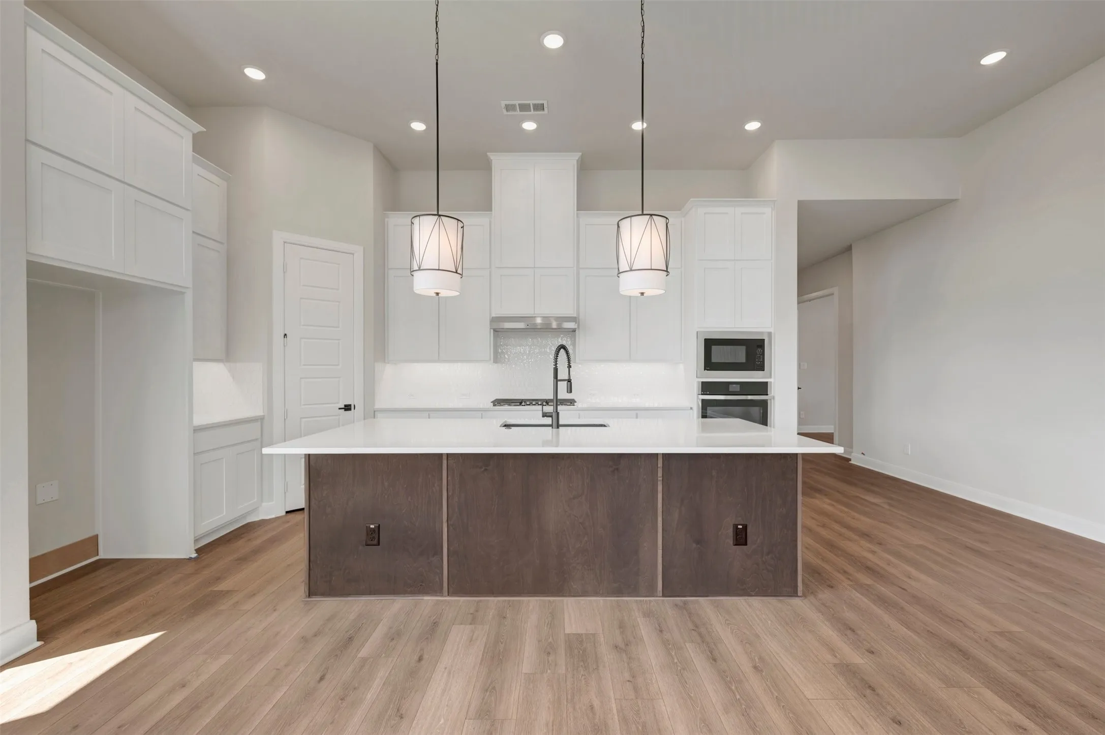 Kitchen with wood-finish flooring, white cabinetry, a center island with a white countertop, and recessed lighting