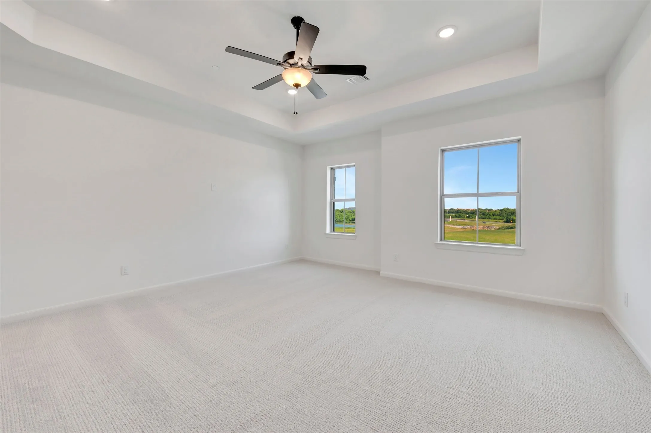 Spacious room featuring a tray ceiling, recessed lighting, and a ceiling fan with integrated light fixture