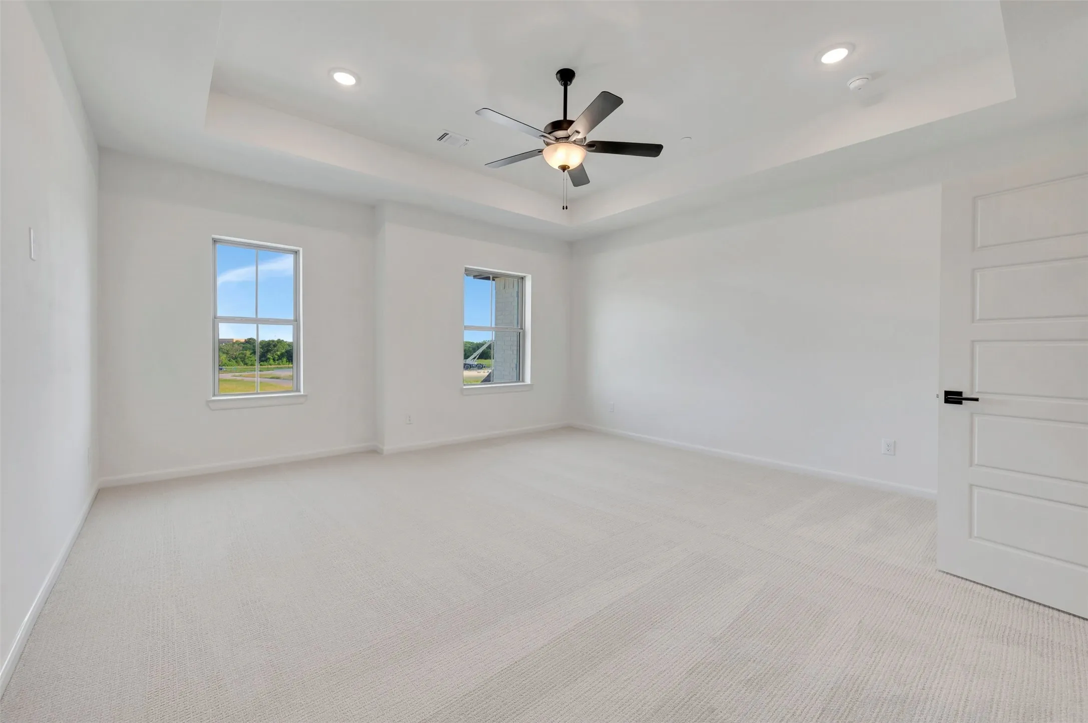 Spacious room featuring a tray ceiling, recessed lighting, and a contemporary ceiling fan
