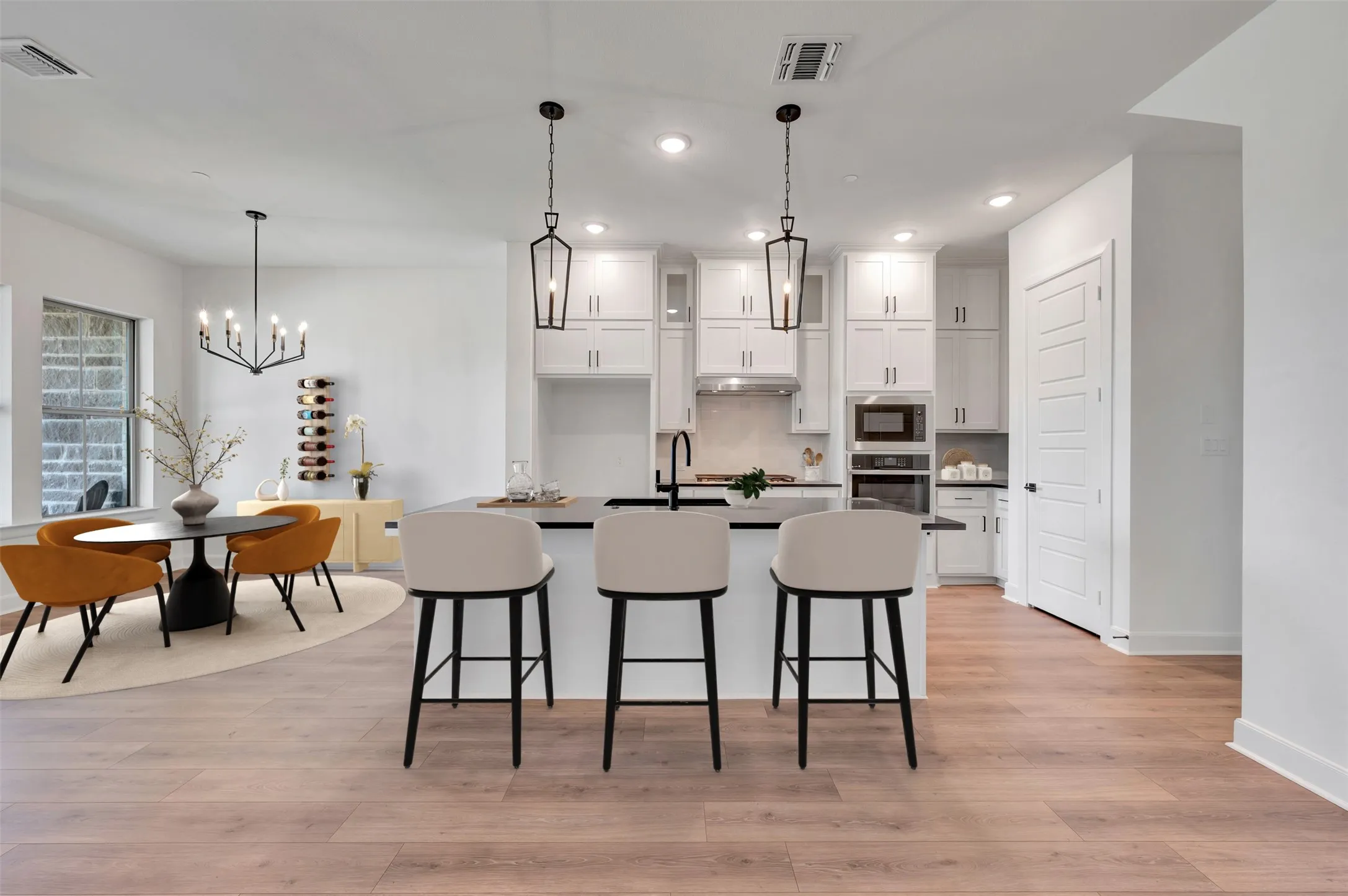 Contemporary kitchen featuring a large island with seating, white cabinetry, dark countertops, and stainless steel appliances