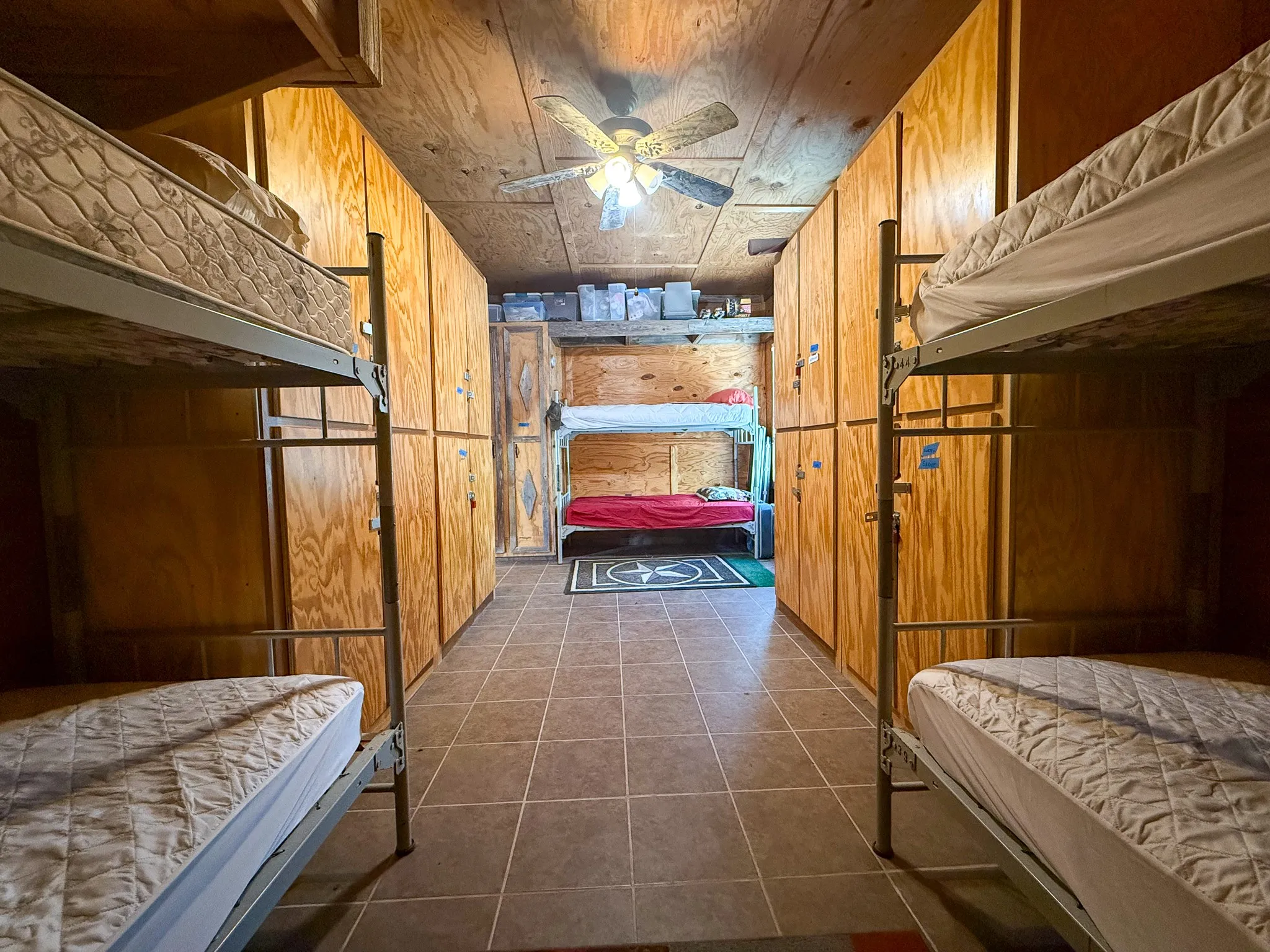 Room featuring extensive built-in wooden cabinetry, tile flooring, and a ceiling fan