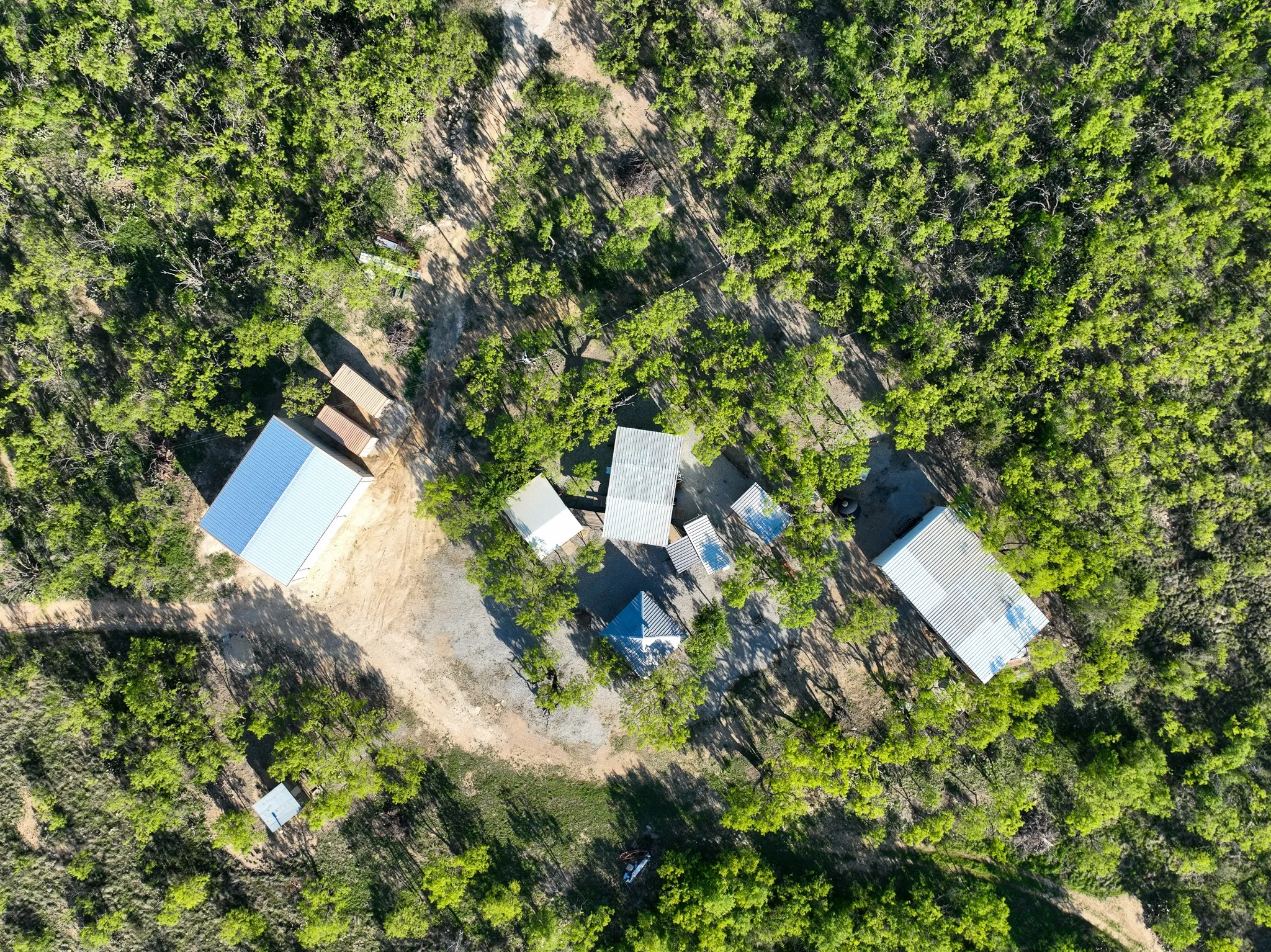 Aerial perspective showcasing multiple structures surrounded by dense, verdant tree canopy