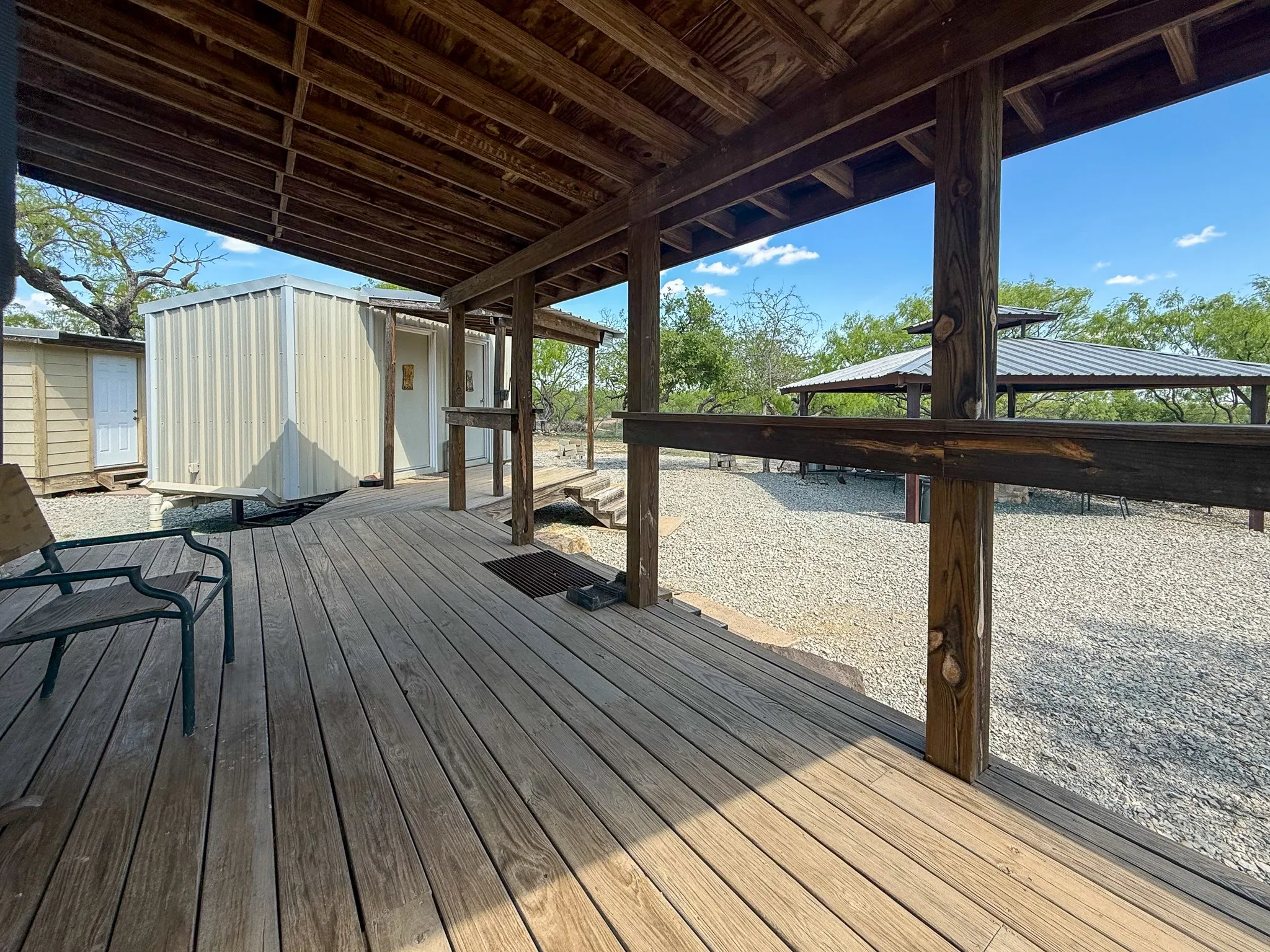 Expansive wood deck with a full-length covered patio, featuring exposed wood beams and posts
