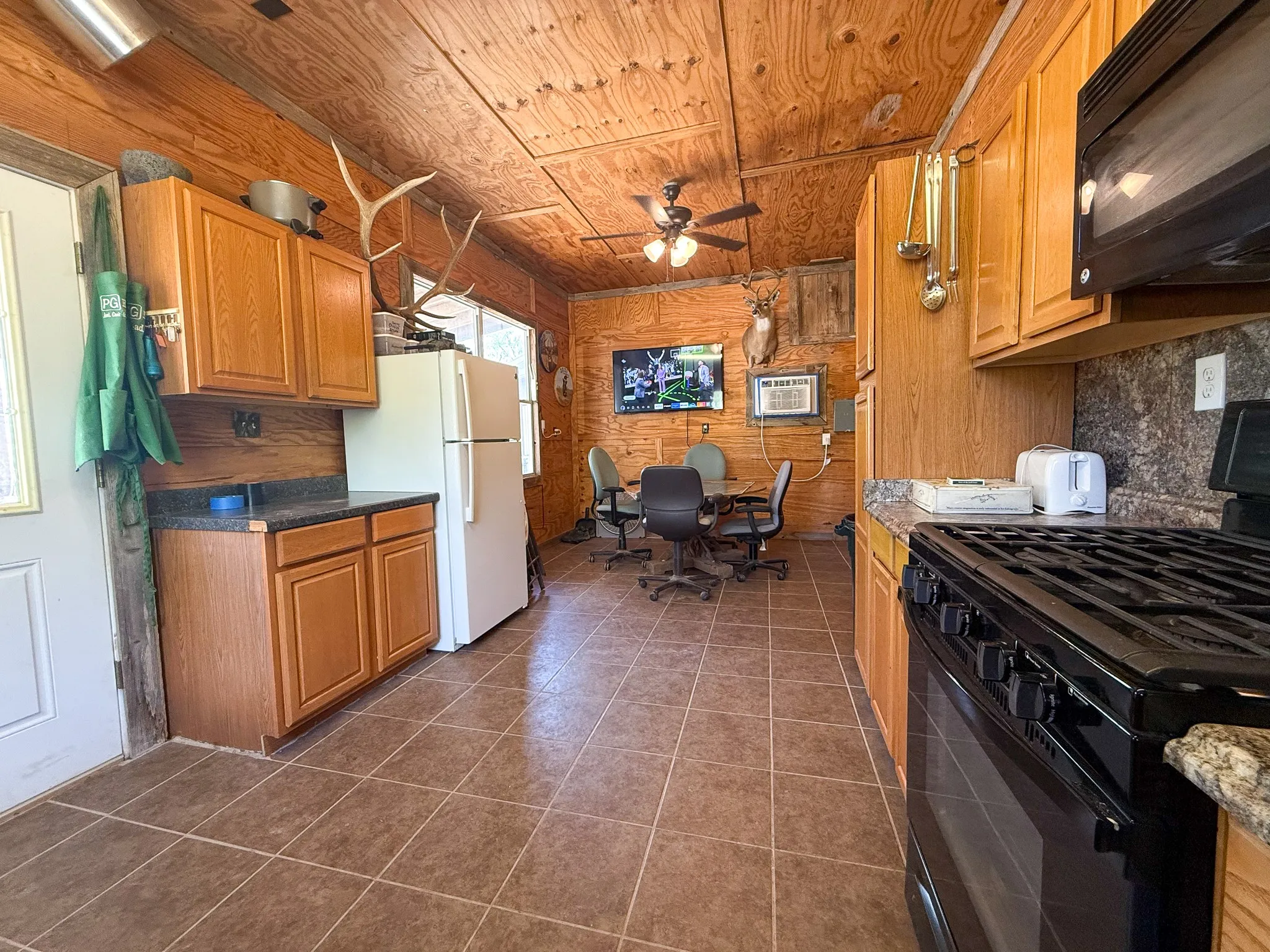 Open-concept kitchen and dining area featuring wood-paneled walls and ceiling